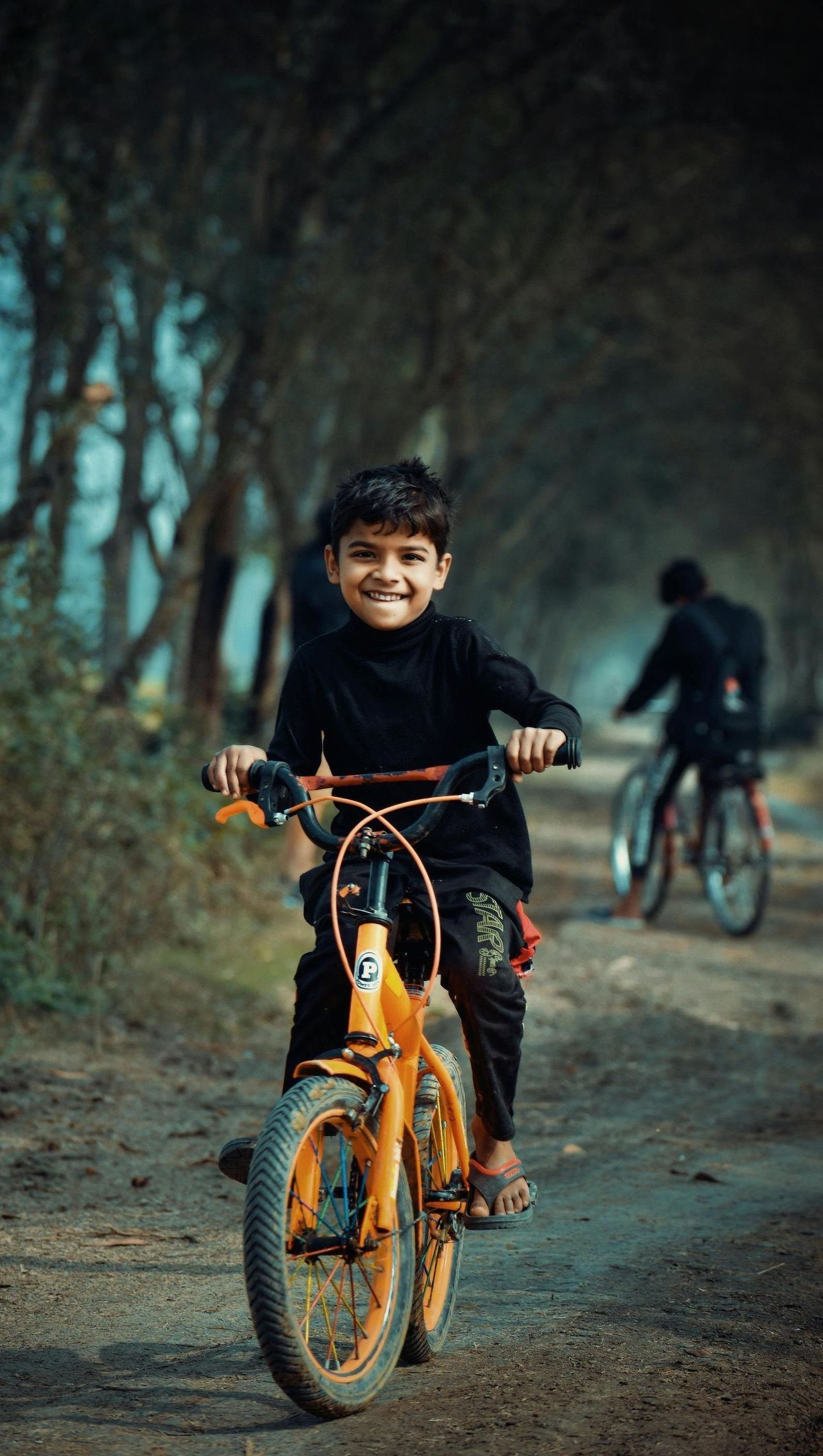 A young boy is riding a bicycle down a dirt road.