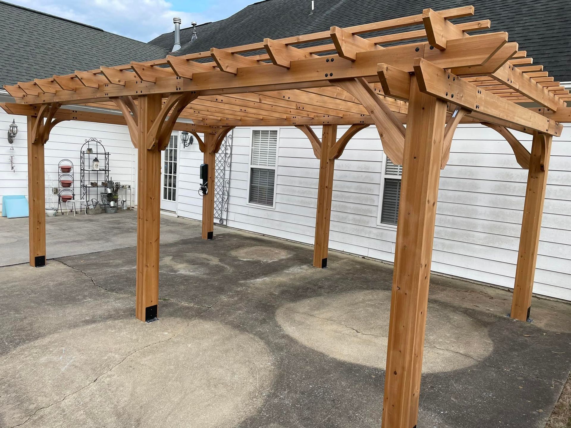Woman in straw hat smiles, holding wine glass near a lake.