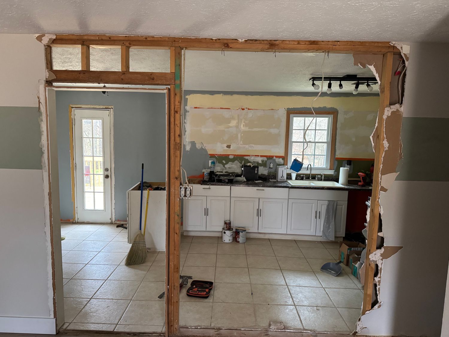 Woman in straw hat smiles, holding wine glass near a lake.