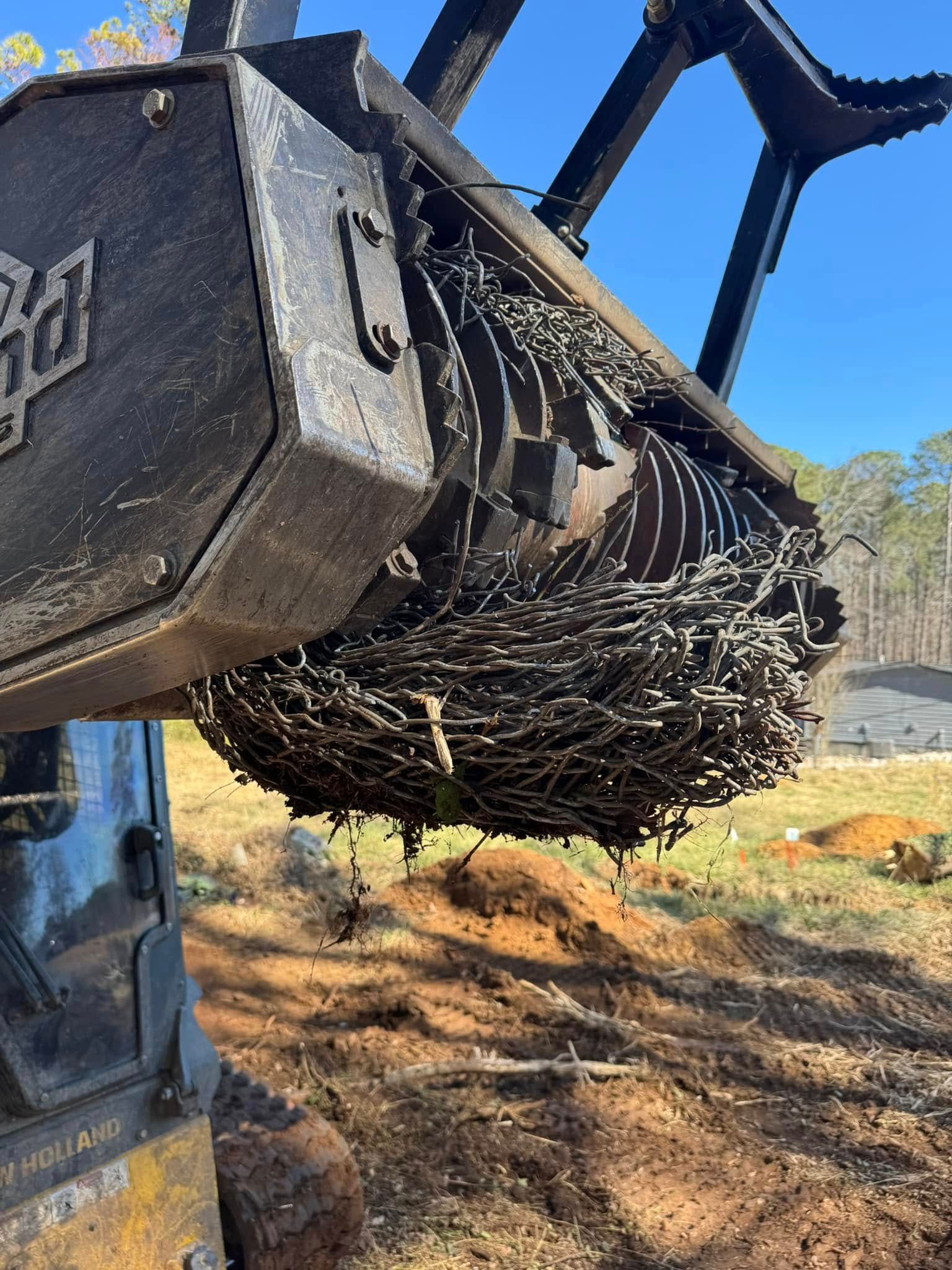 Skid steer attachment with wire debris in a field on a sunny day.
