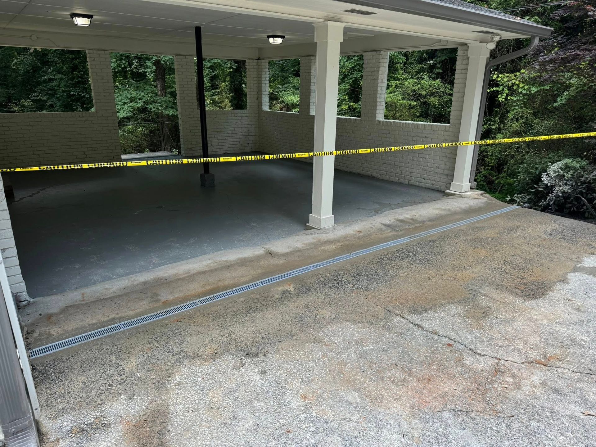 Covered concrete patio with a drainage system and caution tape.