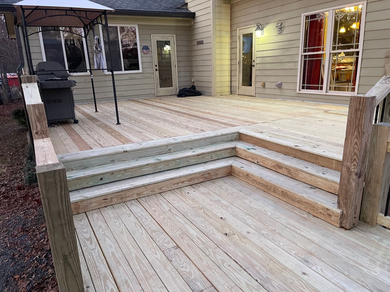 Woman in straw hat smiles, holding wine glass near a lake.