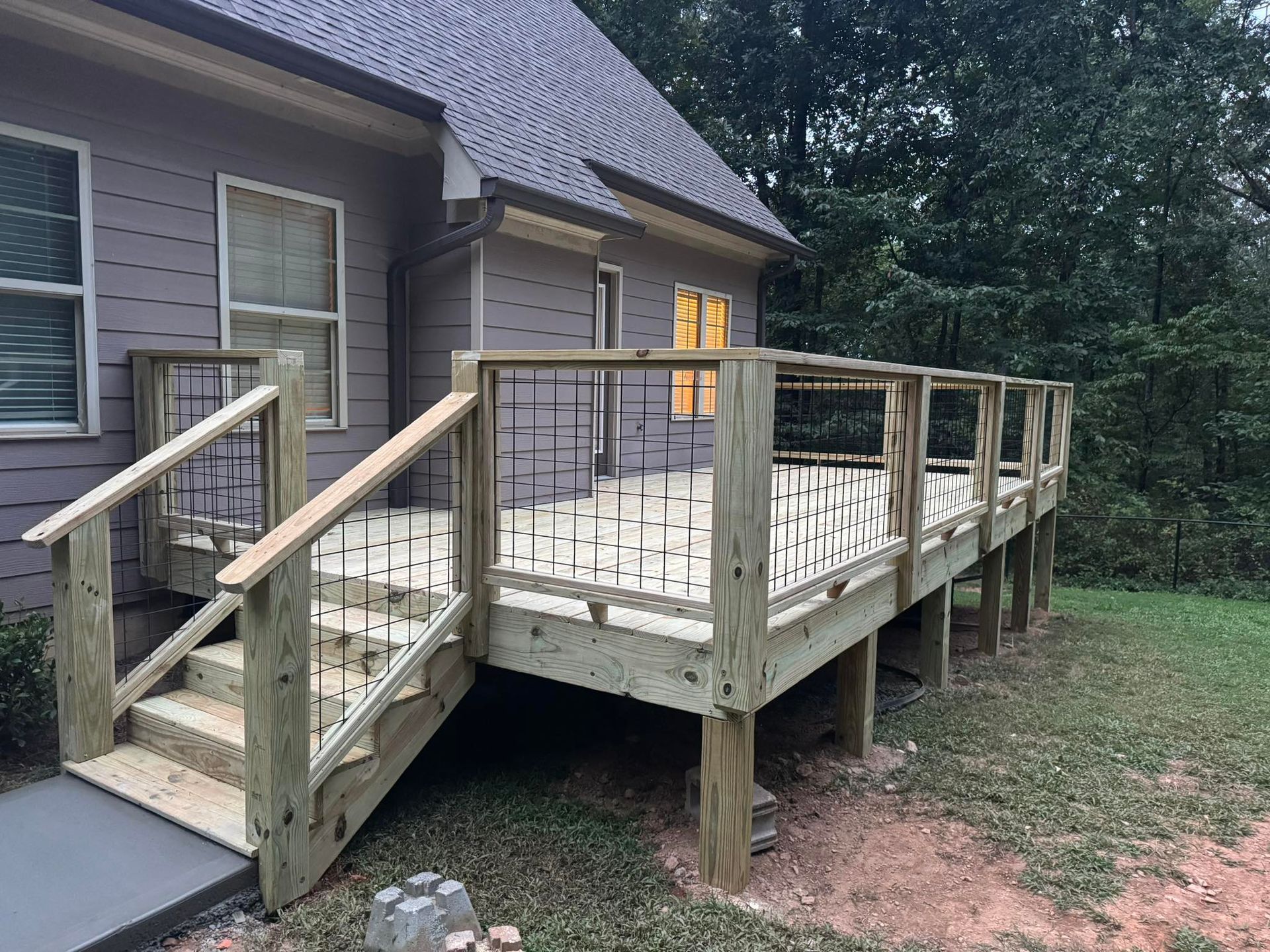 Woman in straw hat smiles, holding wine glass near a lake.