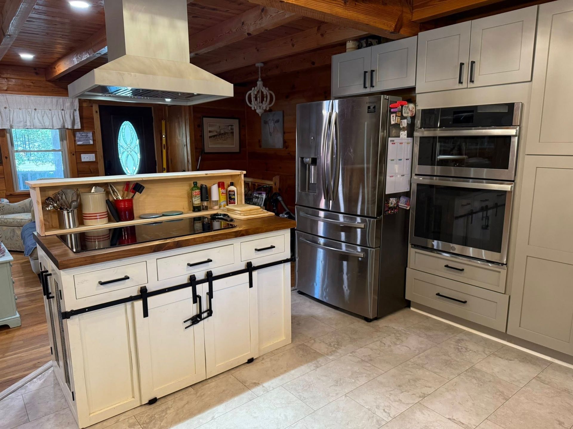 Kitchen with island, stainless steel appliances, light cabinets, and wood paneling.