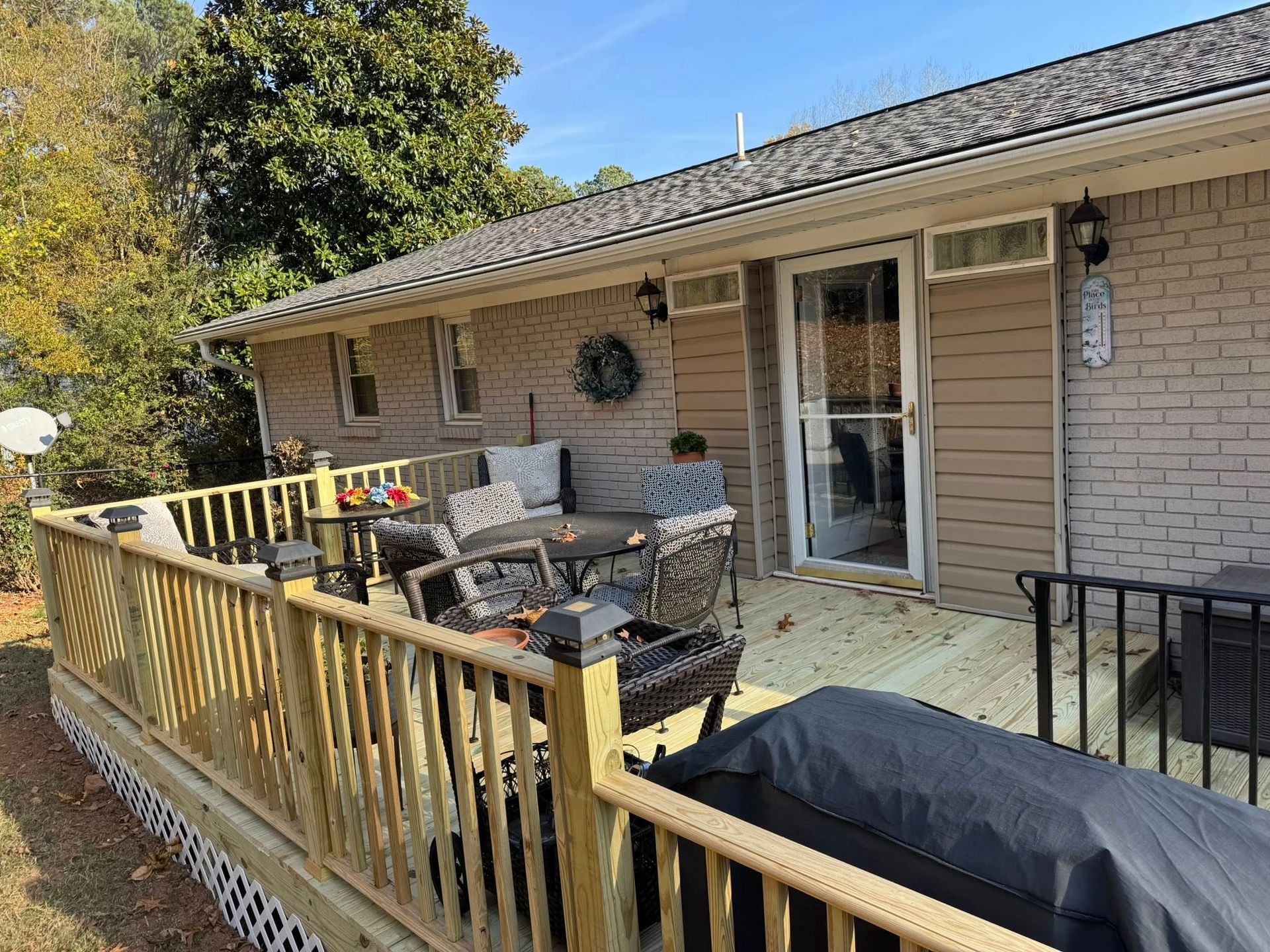 Wooden deck with patio furniture next to a light-colored house.