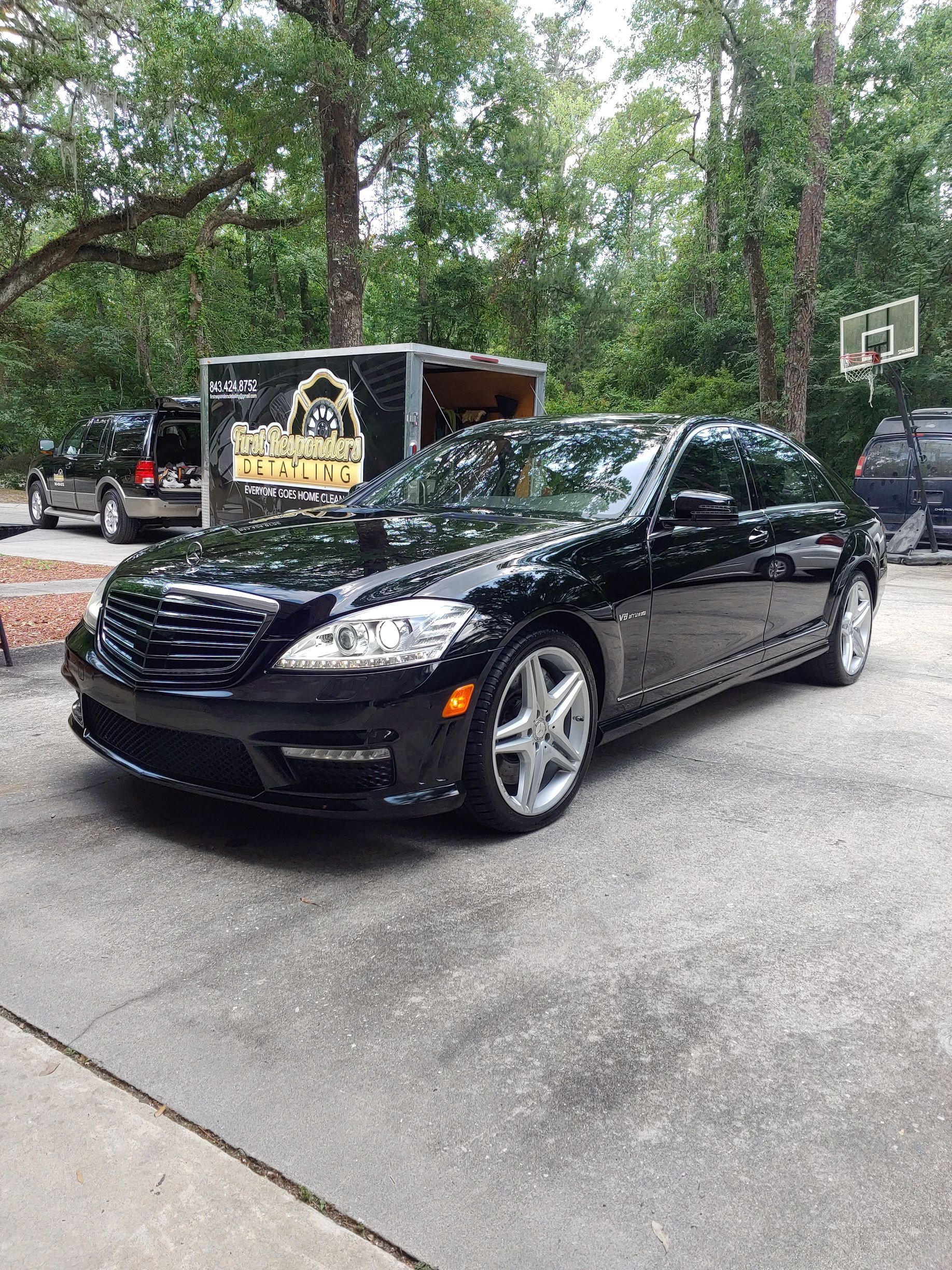 A red cadillac is parked in a garage on a checkered floor.