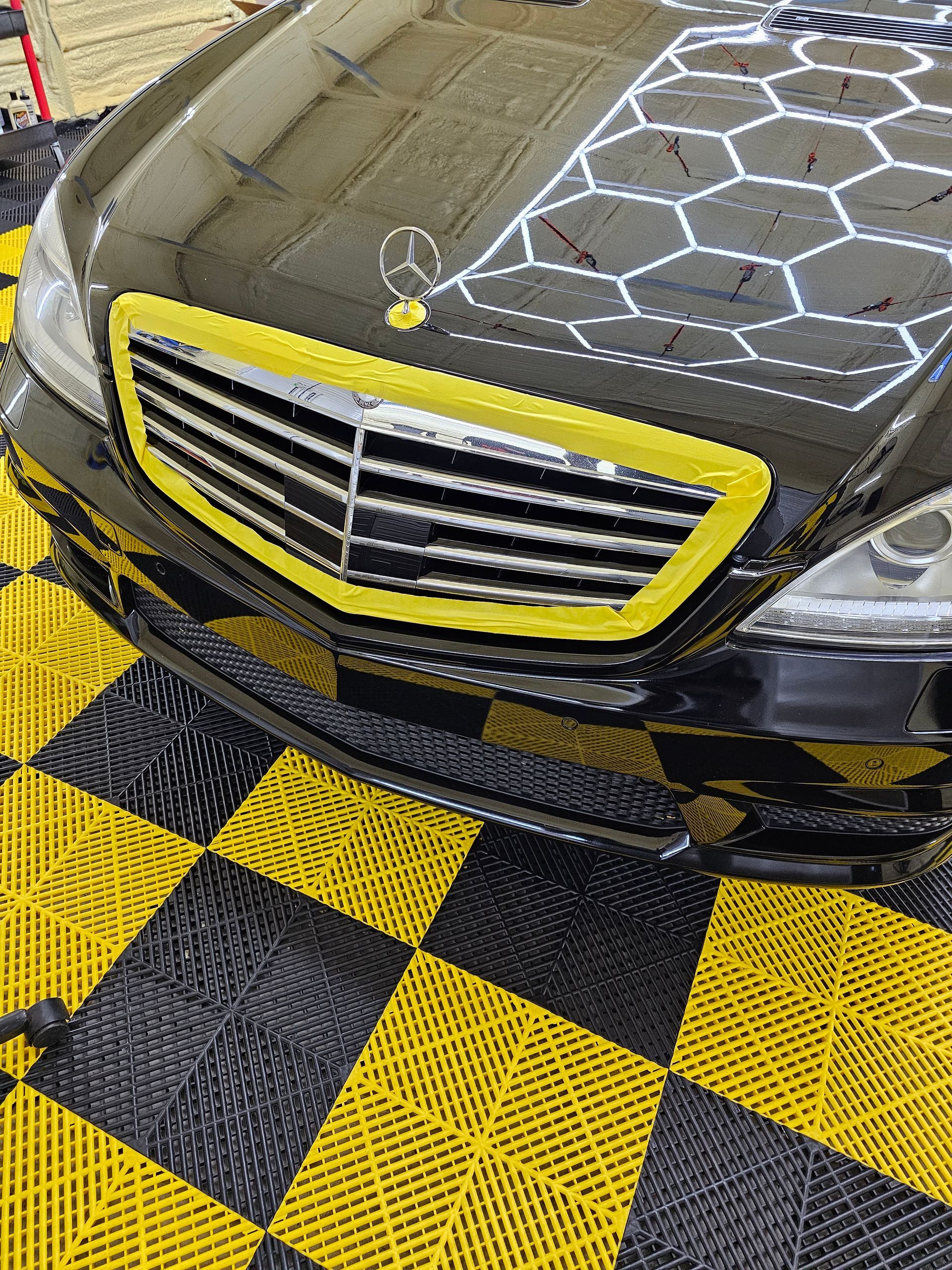 A black mercedes benz is sitting on a yellow and black checkered floor.