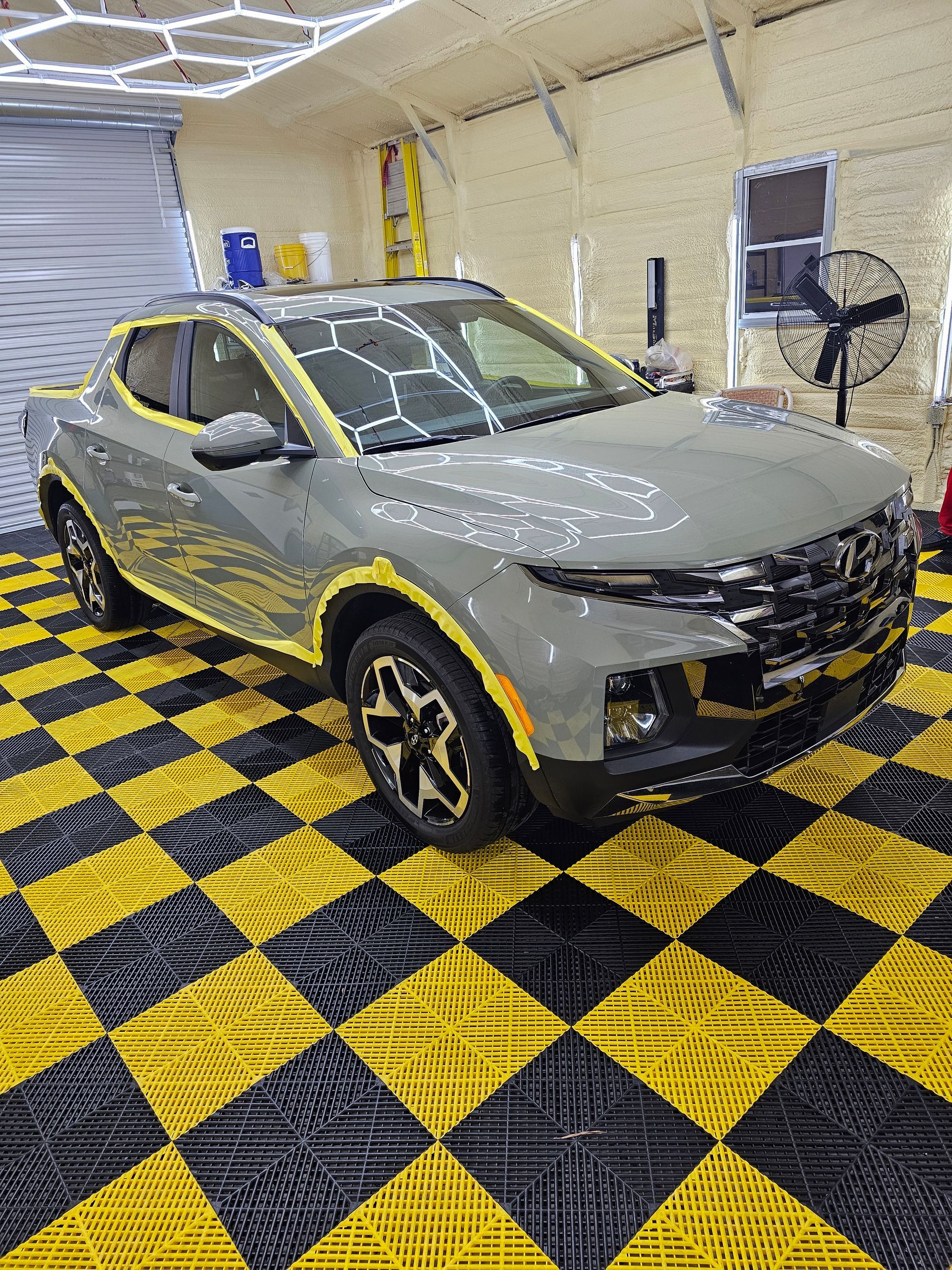 A man is polishing a red car in a garage.