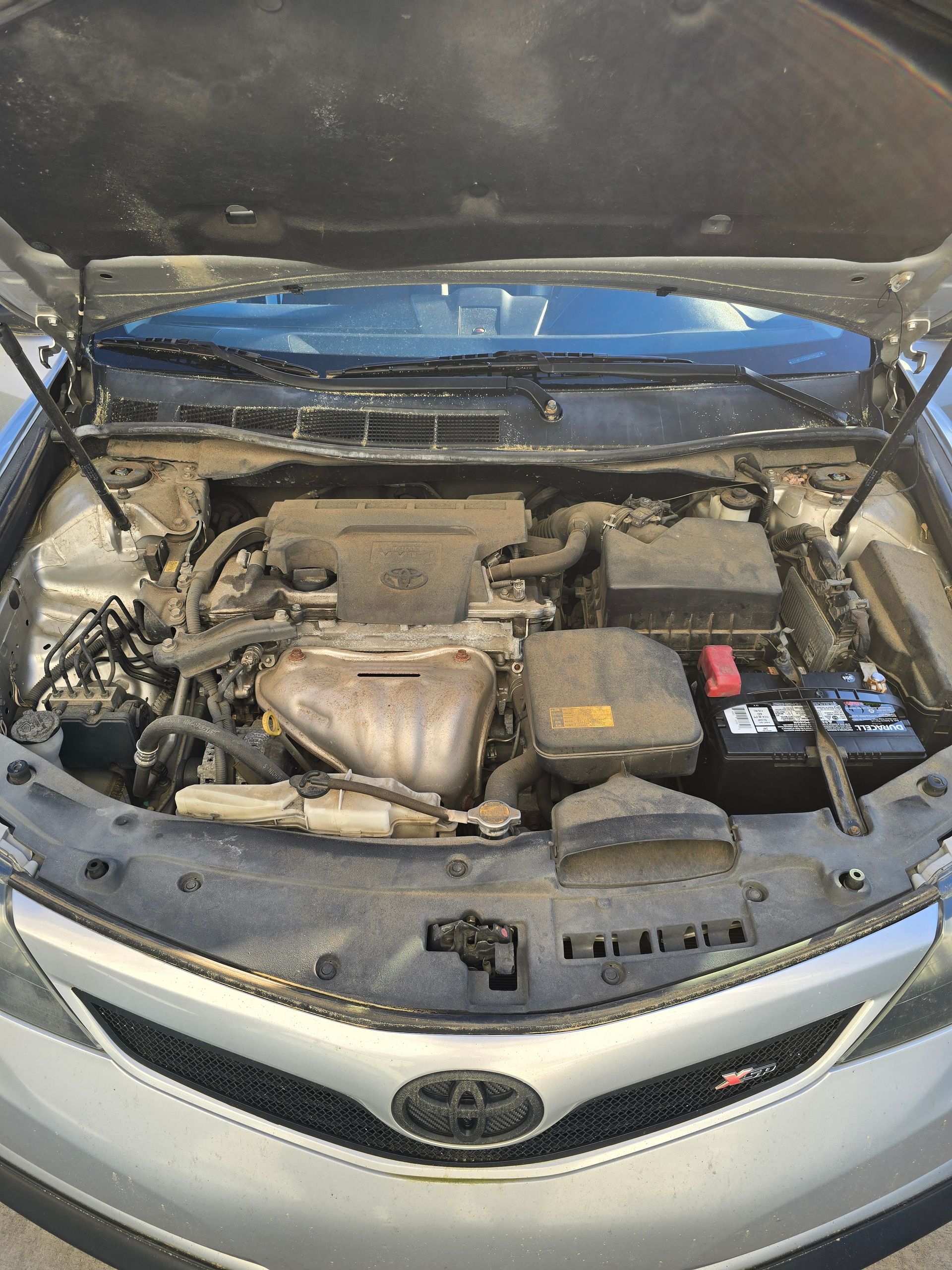 The engine of a toyota camry is shown with the hood open.