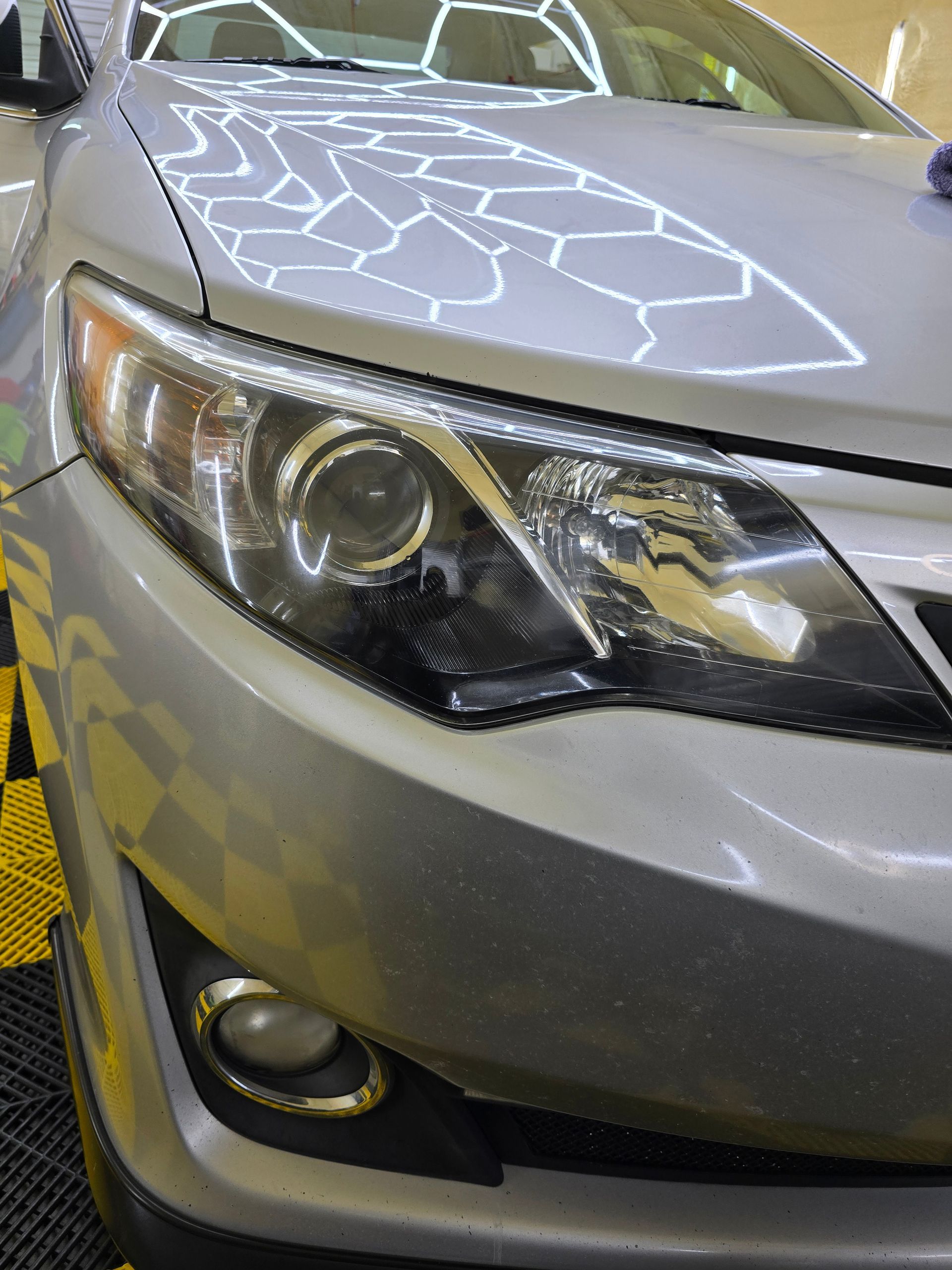 A close up of a car 's headlight and hood.