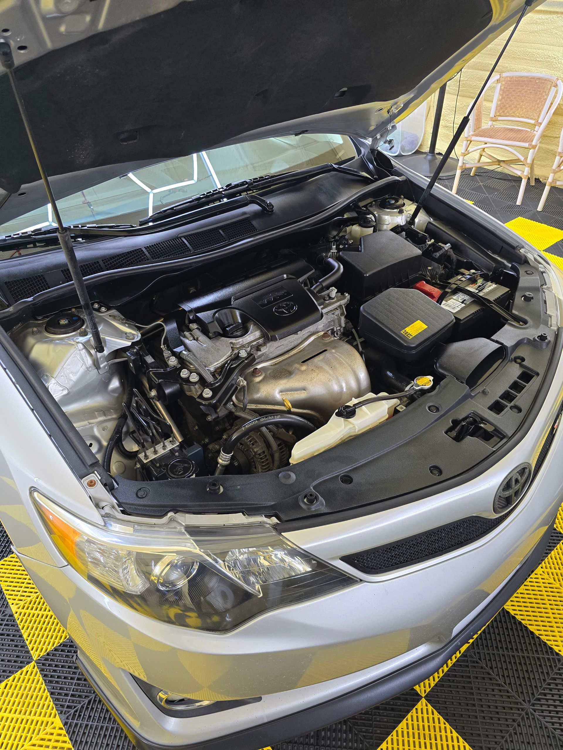 The hood of a silver car is open and the engine is visible.