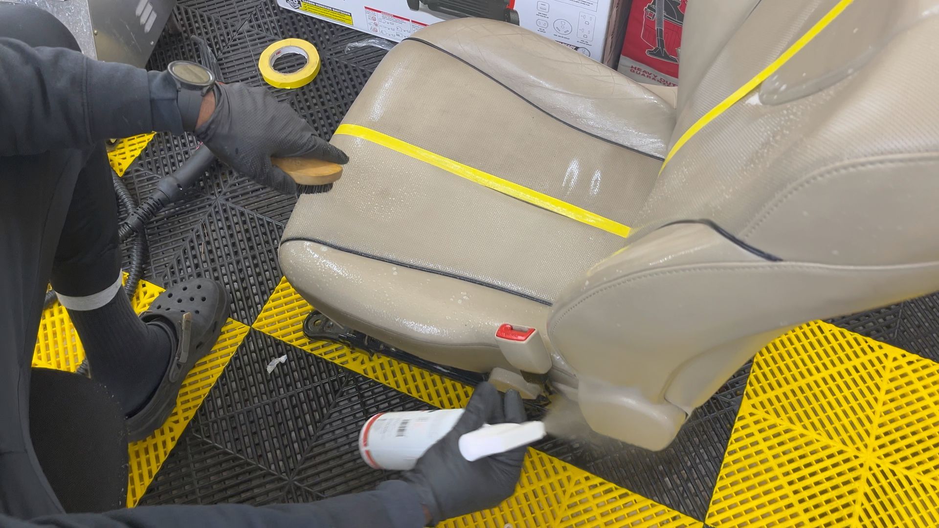 A person is cleaning the carpet of a car with a vacuum cleaner.