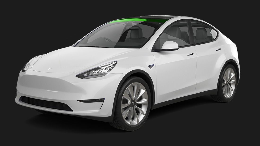 A white tesla model y with a green roof on a black background.