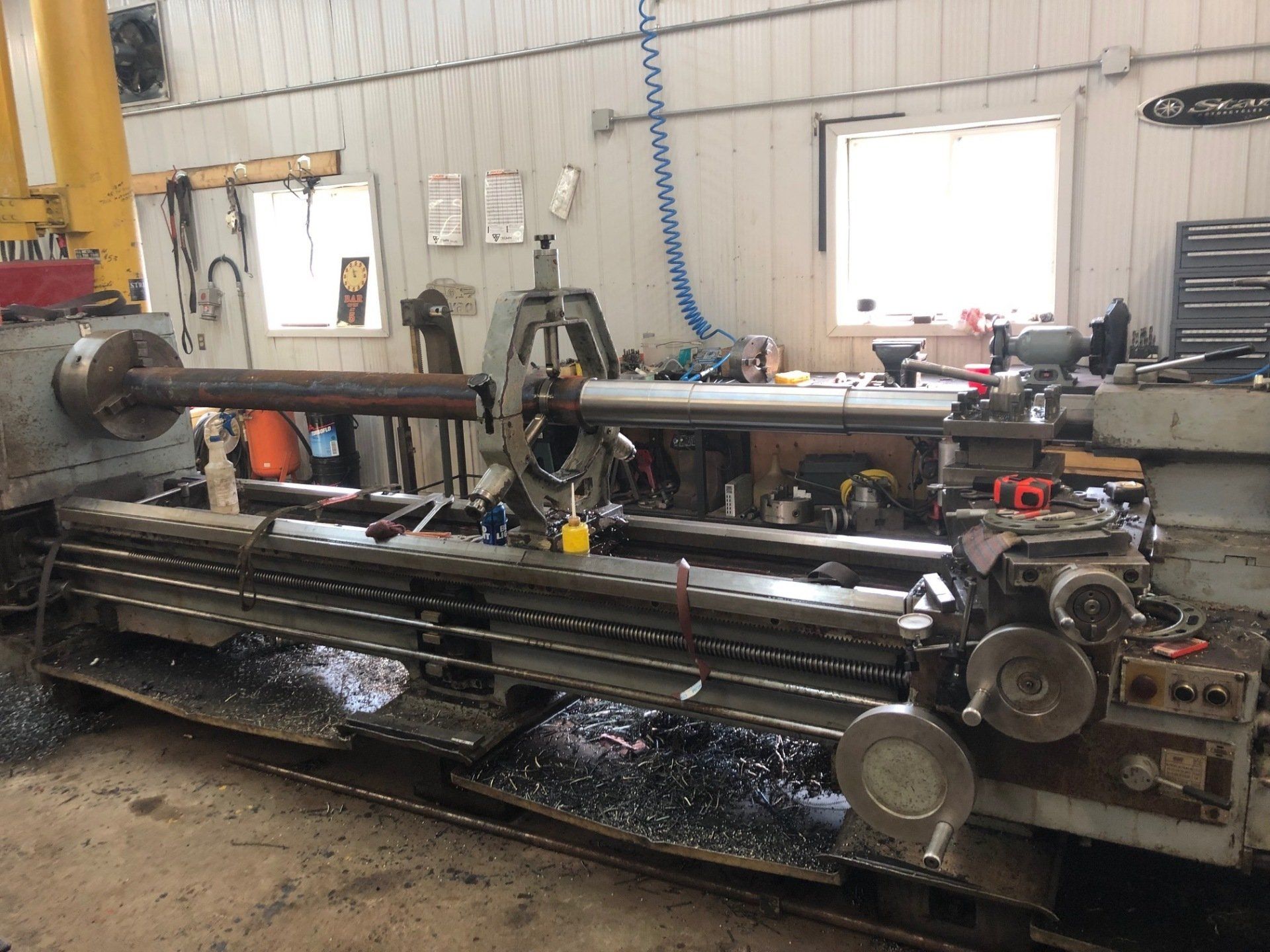A large lathe is sitting in a garage next to a window.