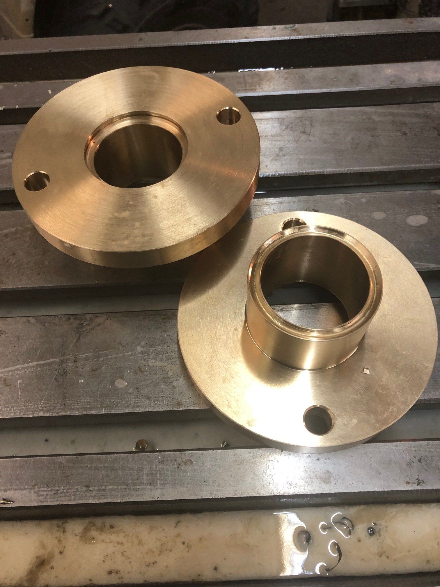 Two brass pieces are sitting on top of a metal table.