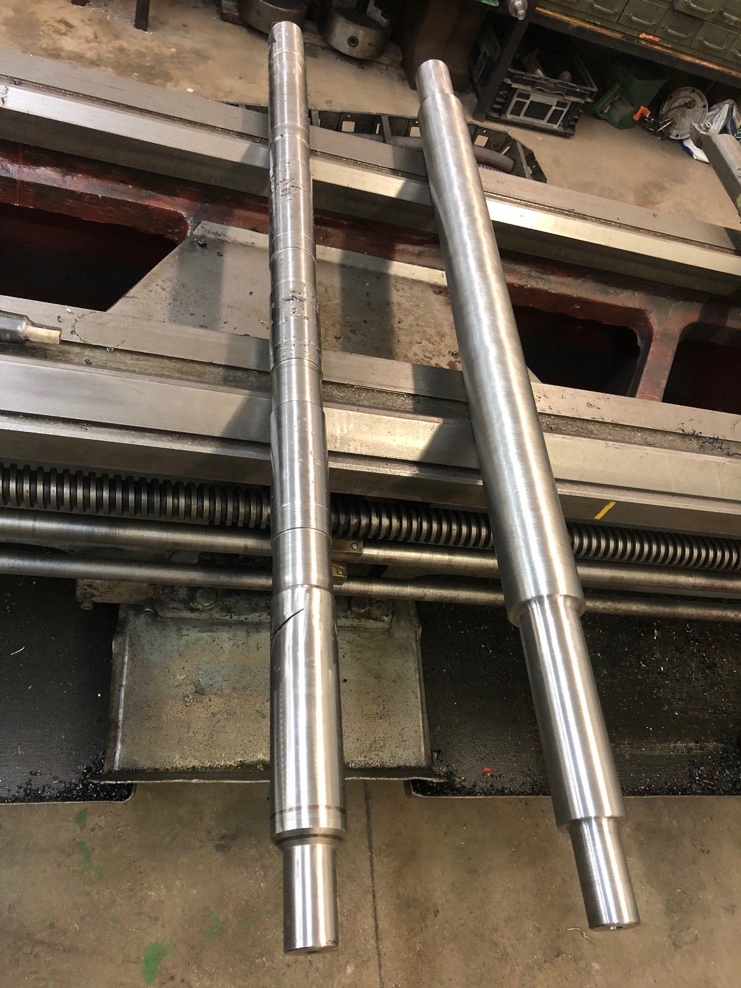 Two stainless steel rods are sitting on top of a lathe.