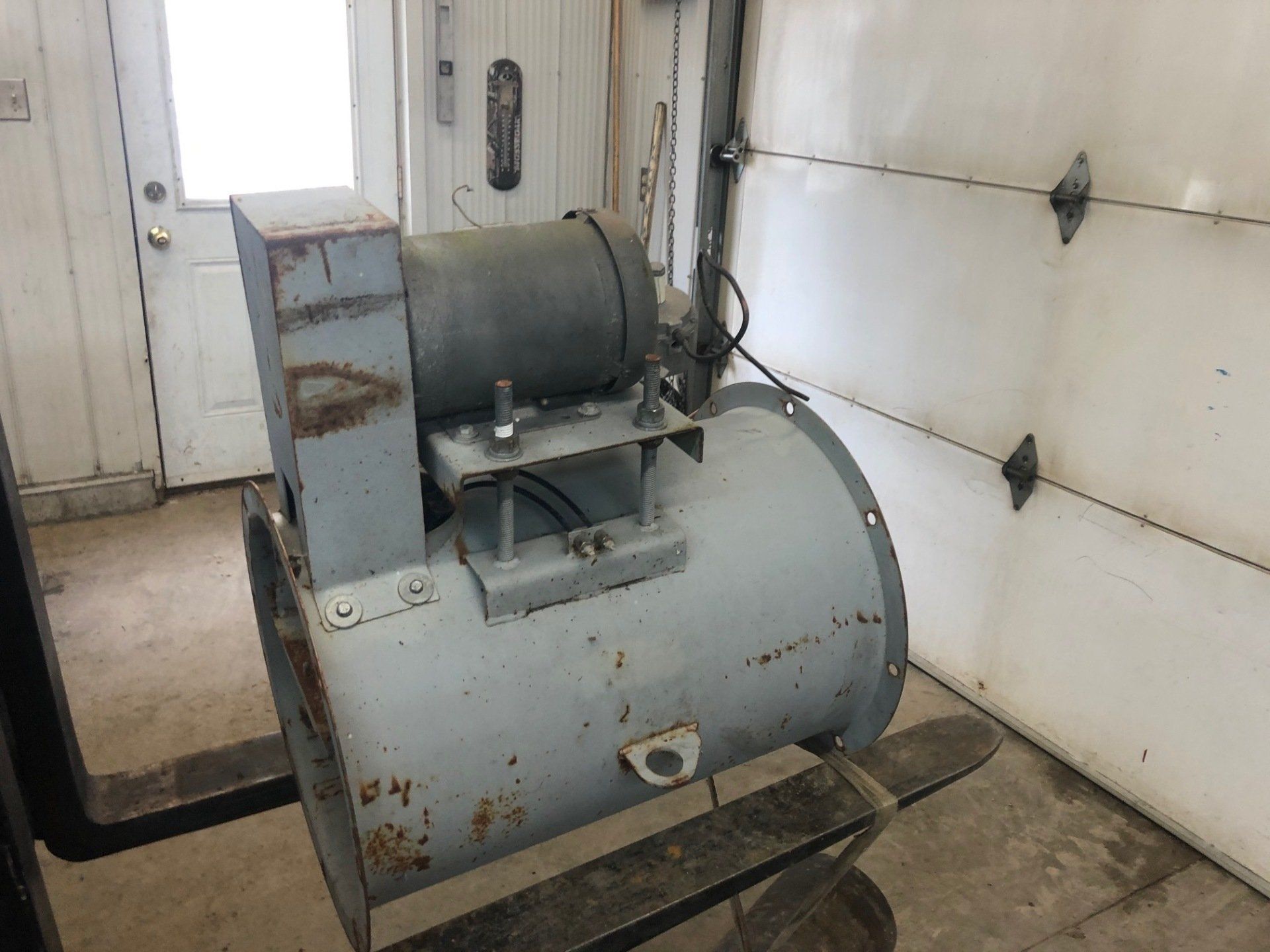 A large machine is sitting in a garage next to a garage door.