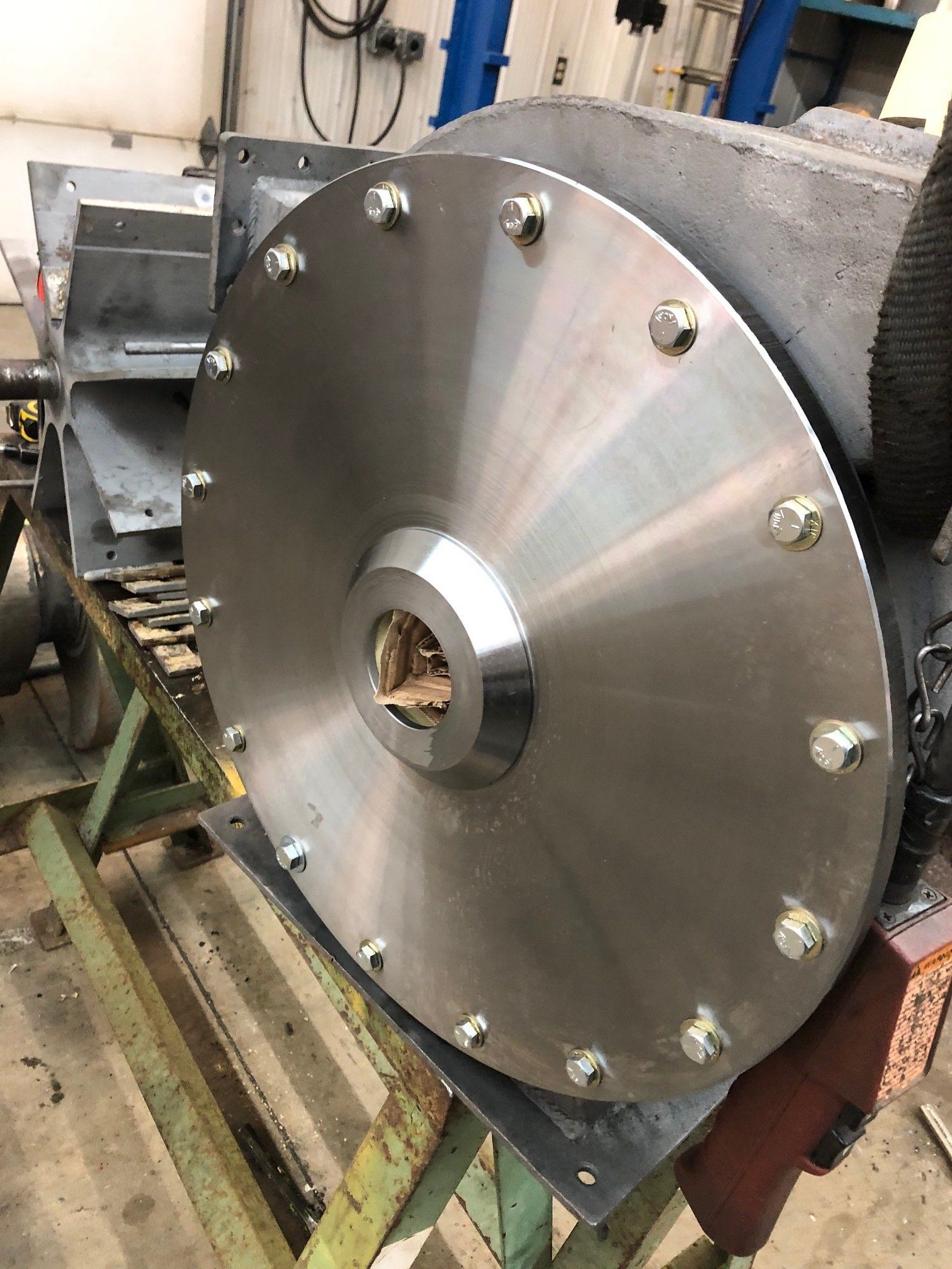 A large stainless steel disc is sitting on top of a machine.