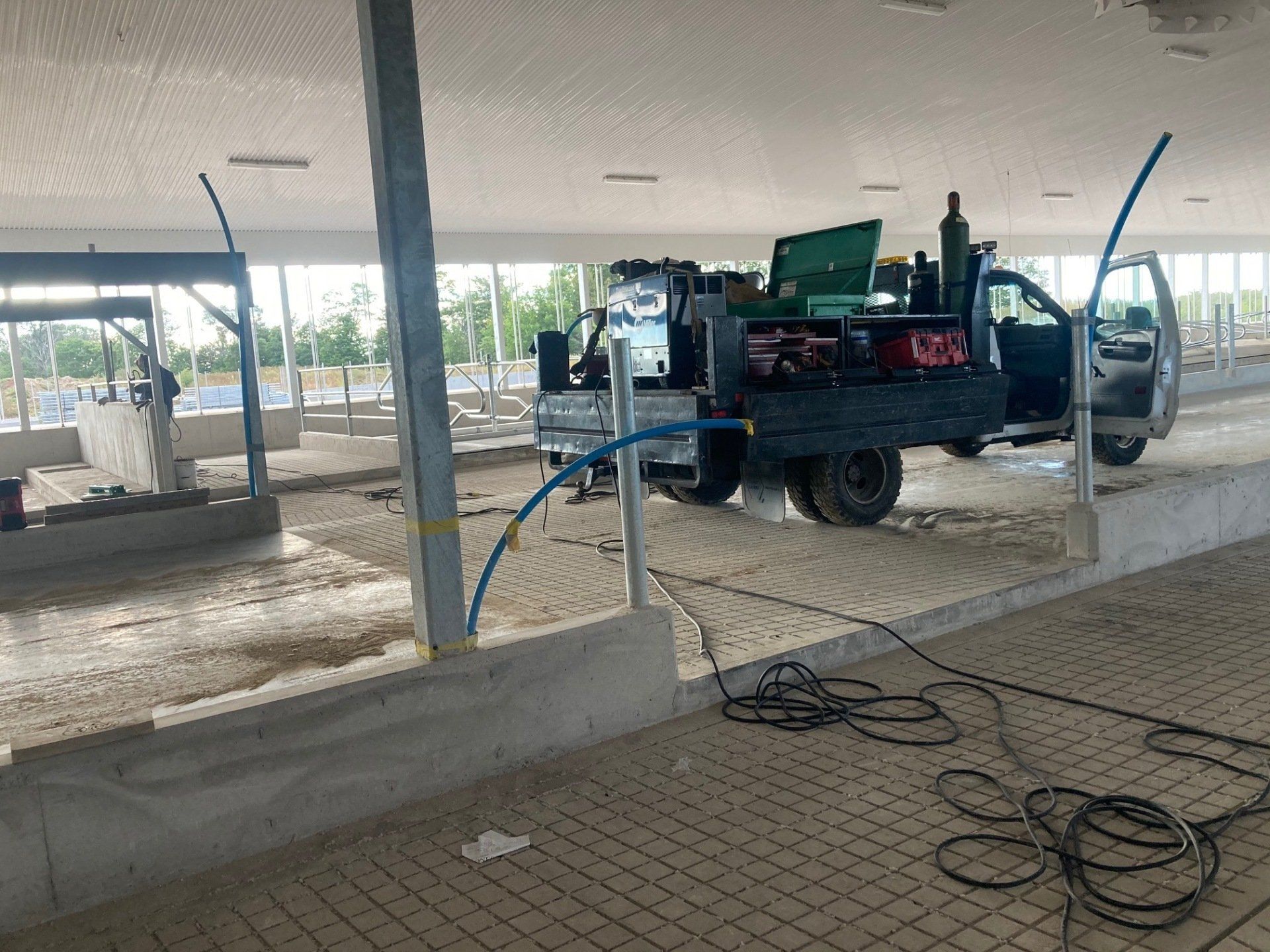 A truck is parked in a barn with a hose attached to it.