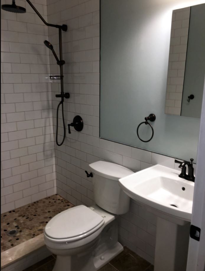 A bathroom with a toilet a sink and a shower