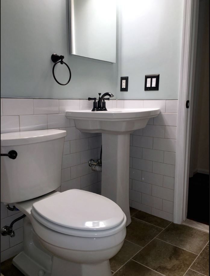 A bathroom with a toilet a sink and a mirror
