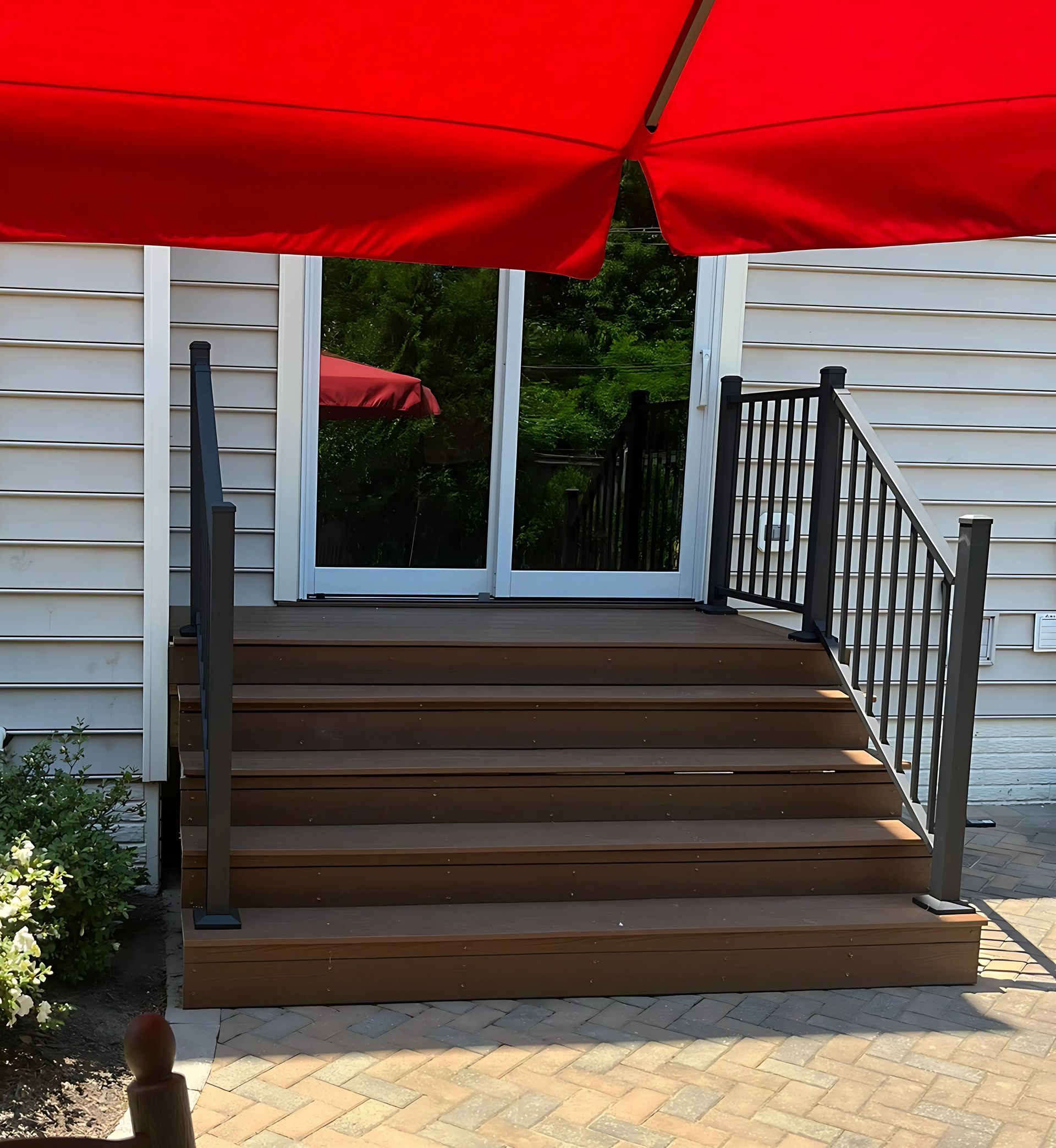 A red umbrella is in front of a white house