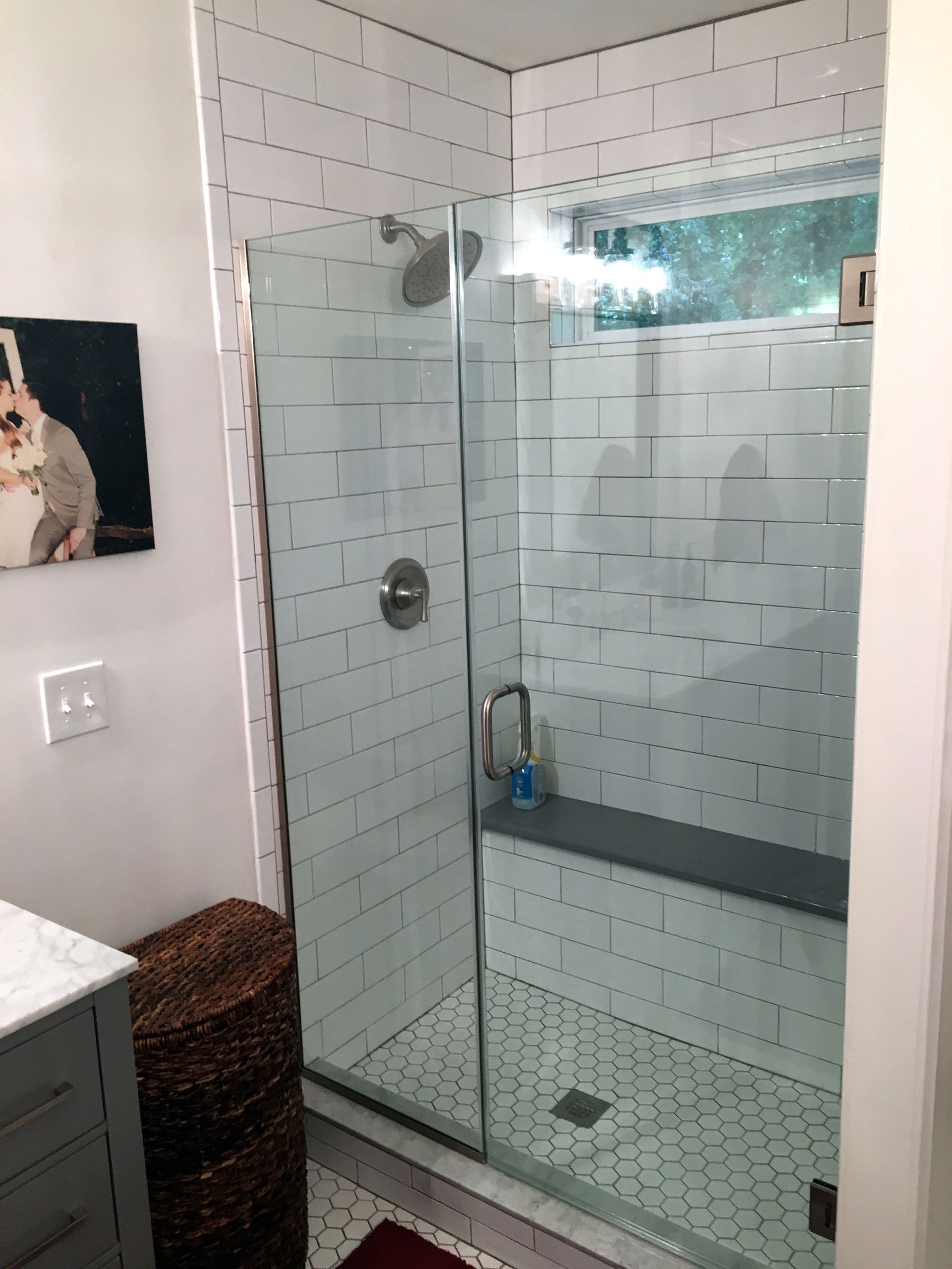 A bathroom with a walk in shower and a picture of a cat on the wall.