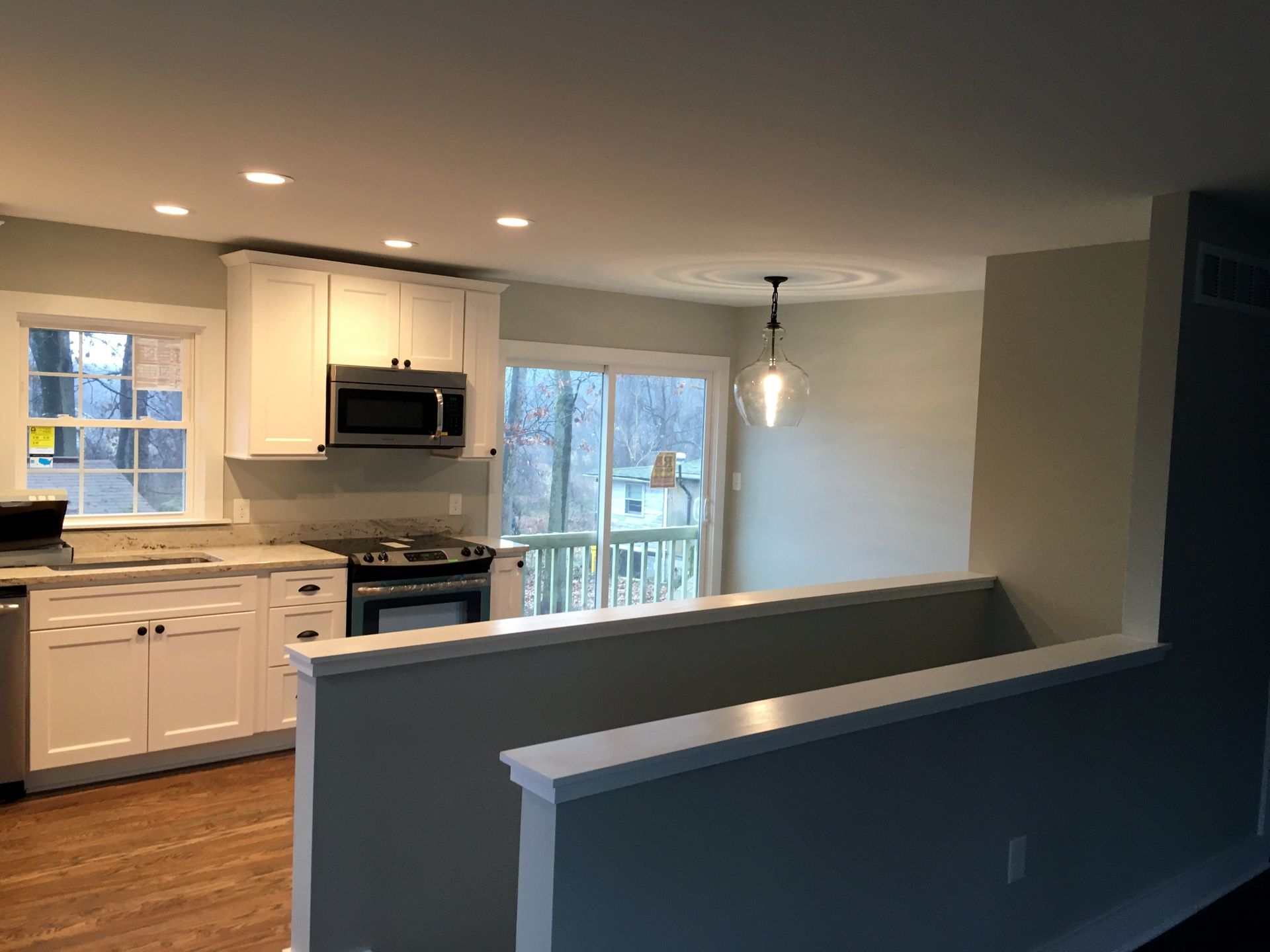 A kitchen with white cabinets and stainless steel appliances and a sliding glass door.