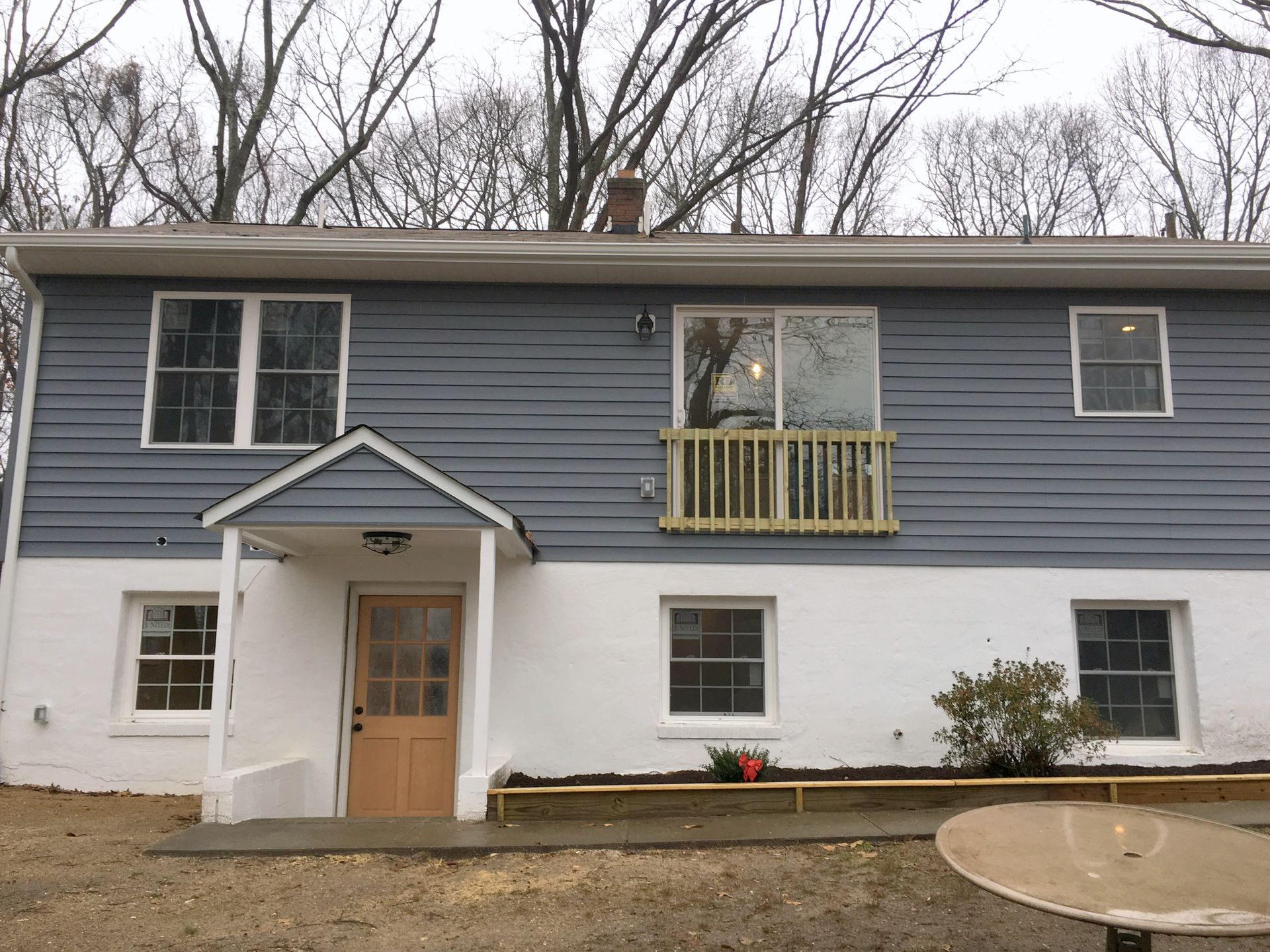 A blue and white house with a porch and a table in front of it