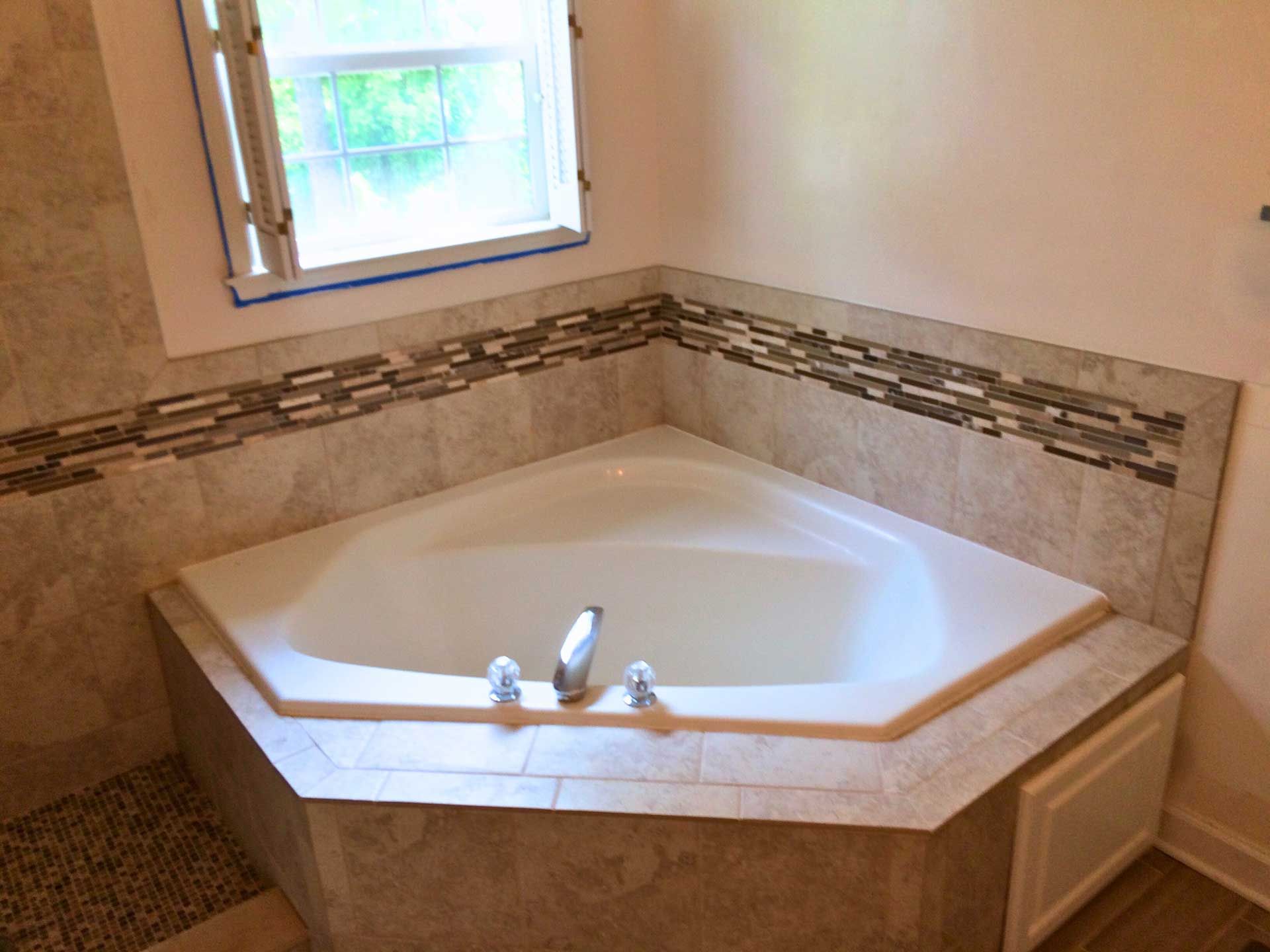 A bathtub in the corner of a bathroom next to a window.