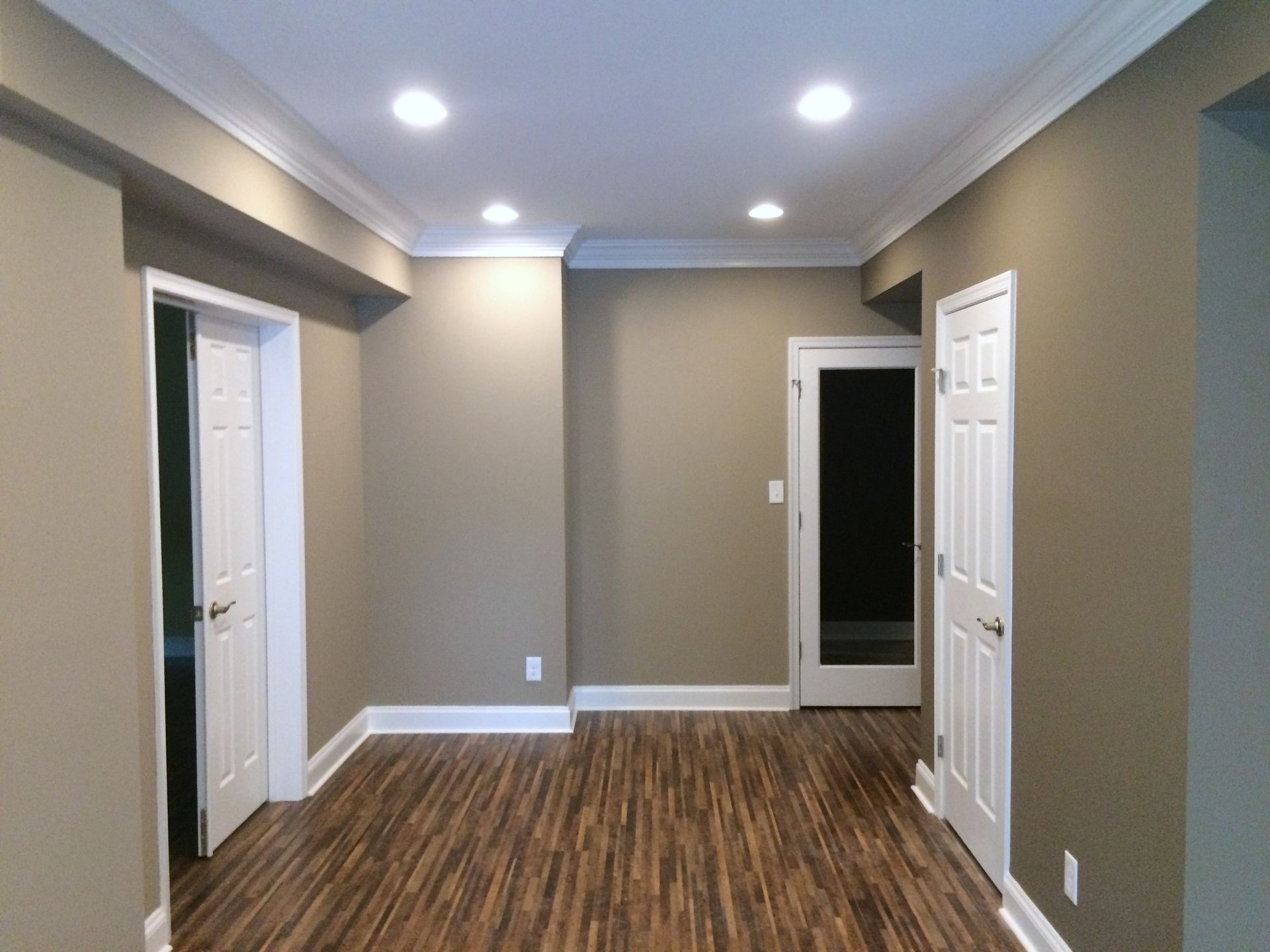 An empty room with hardwood floors and brown walls.