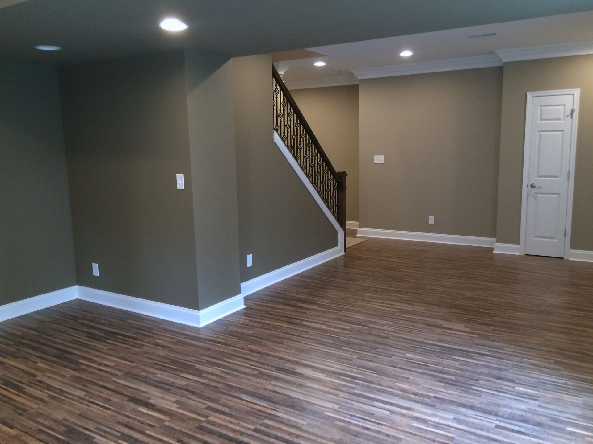 An empty basement with hardwood floors and stairs.