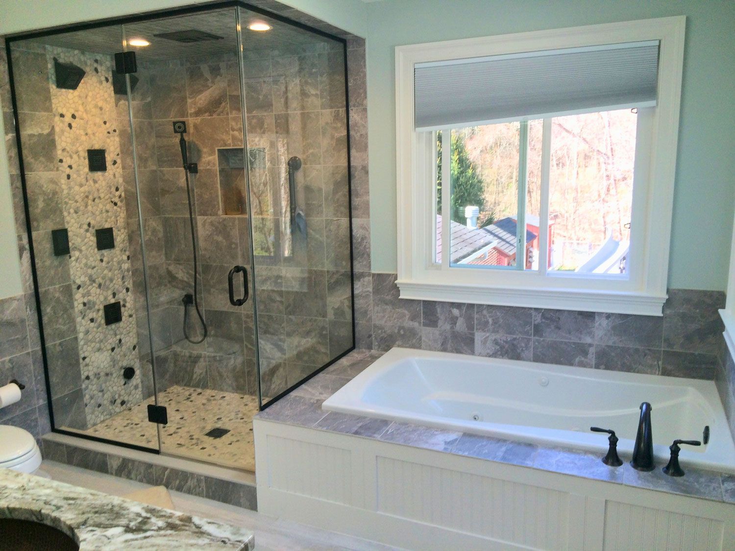 A bathroom with a tub , shower , sink and window.