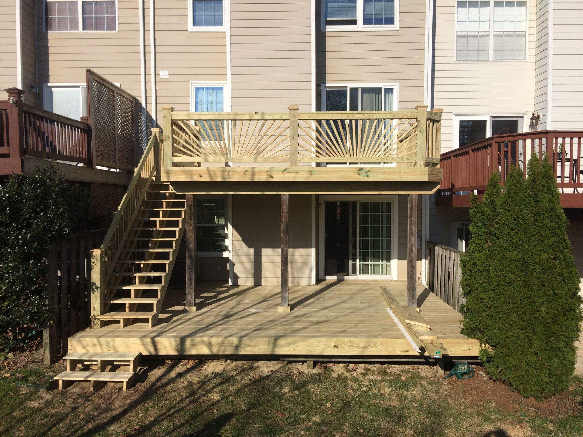 A wooden deck with stairs is in front of a house.