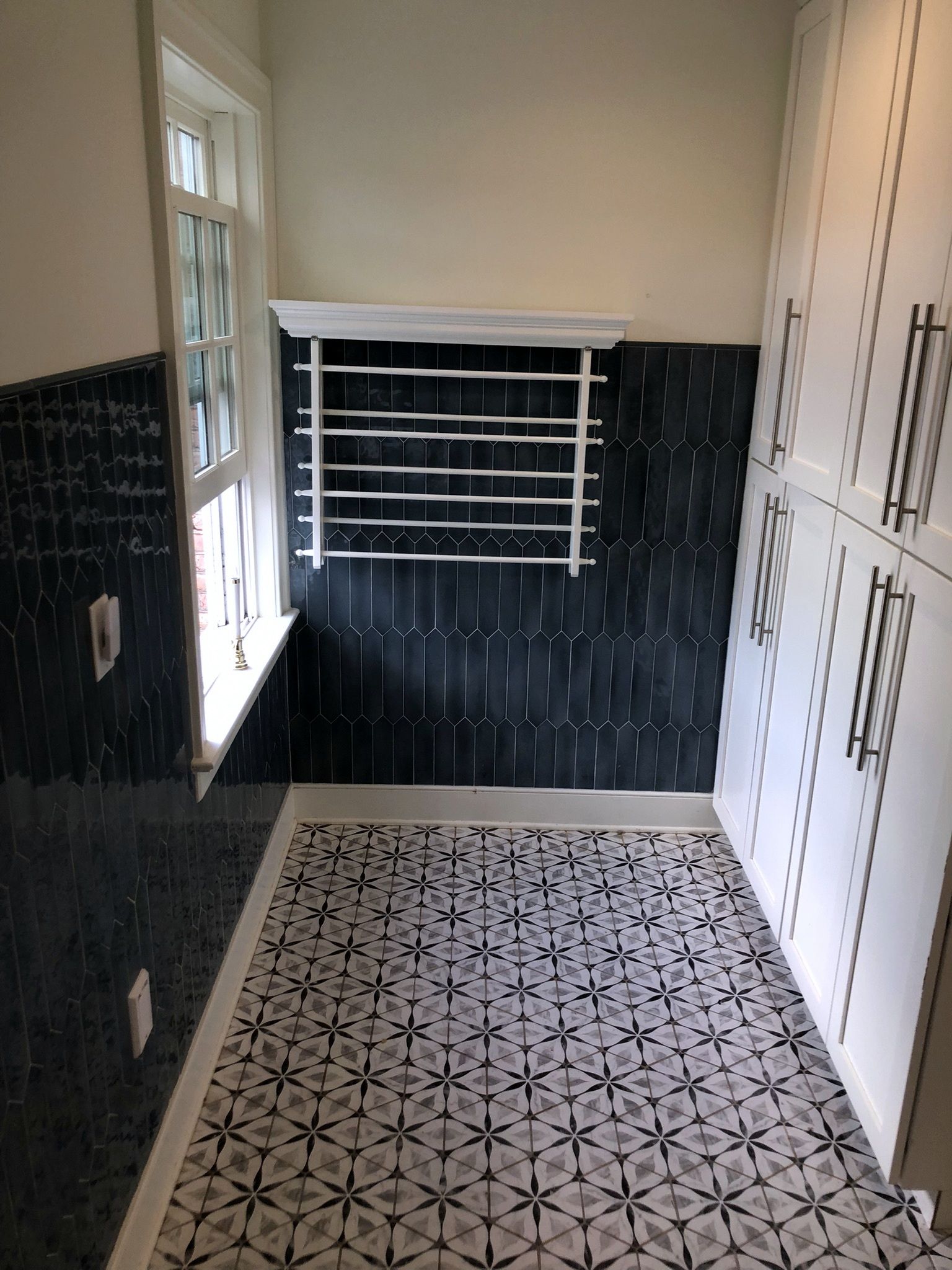 A bathroom with black and white tiles and a window.