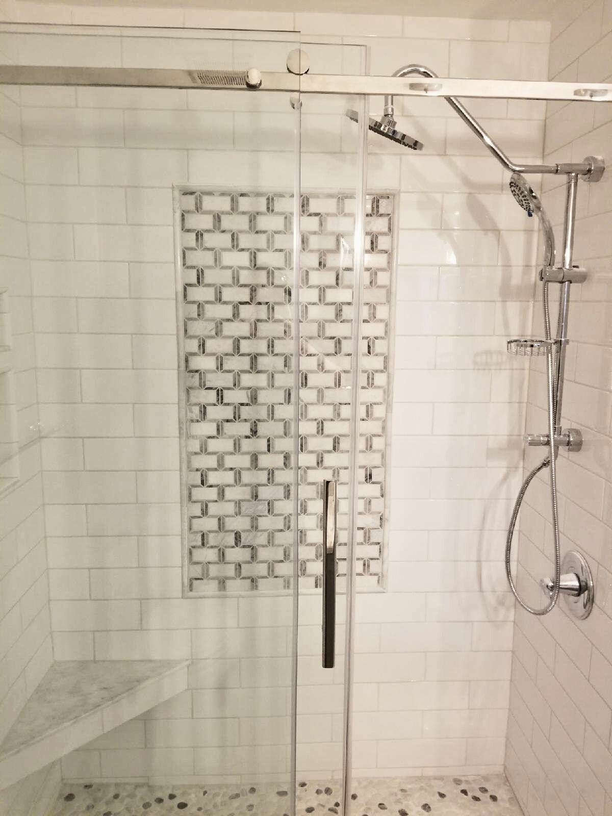 A shower with a sliding glass door and a shower head.