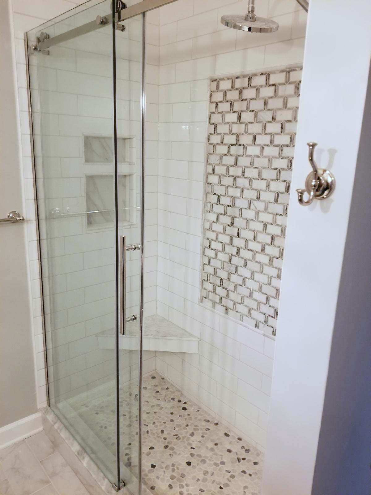 A bathroom with a walk in shower with a sliding glass door.