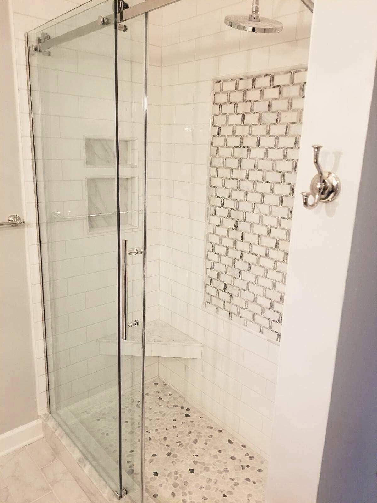 A bathroom with a walk in shower with a sliding glass door.