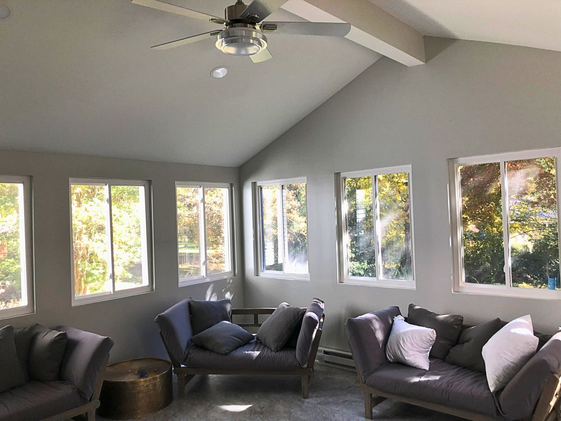A living room with a lot of windows and a ceiling fan.