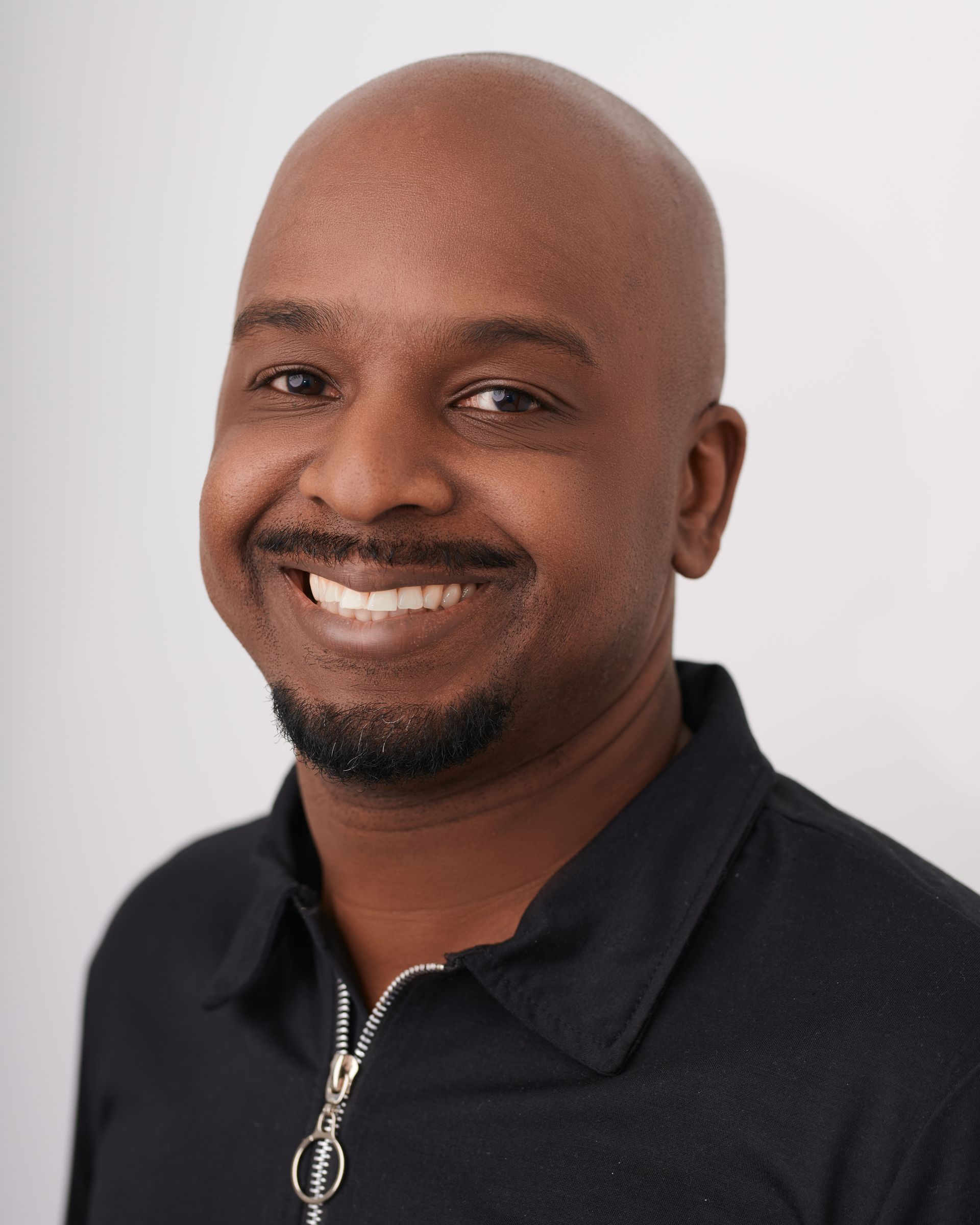 Un homme chauve avec une barbe sourit à la caméra