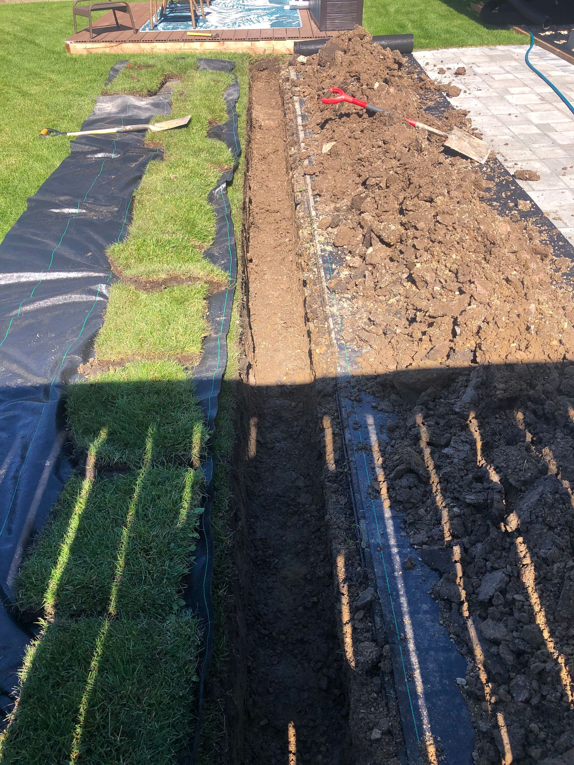 A field of grass and dirt is being installed in a backyard.