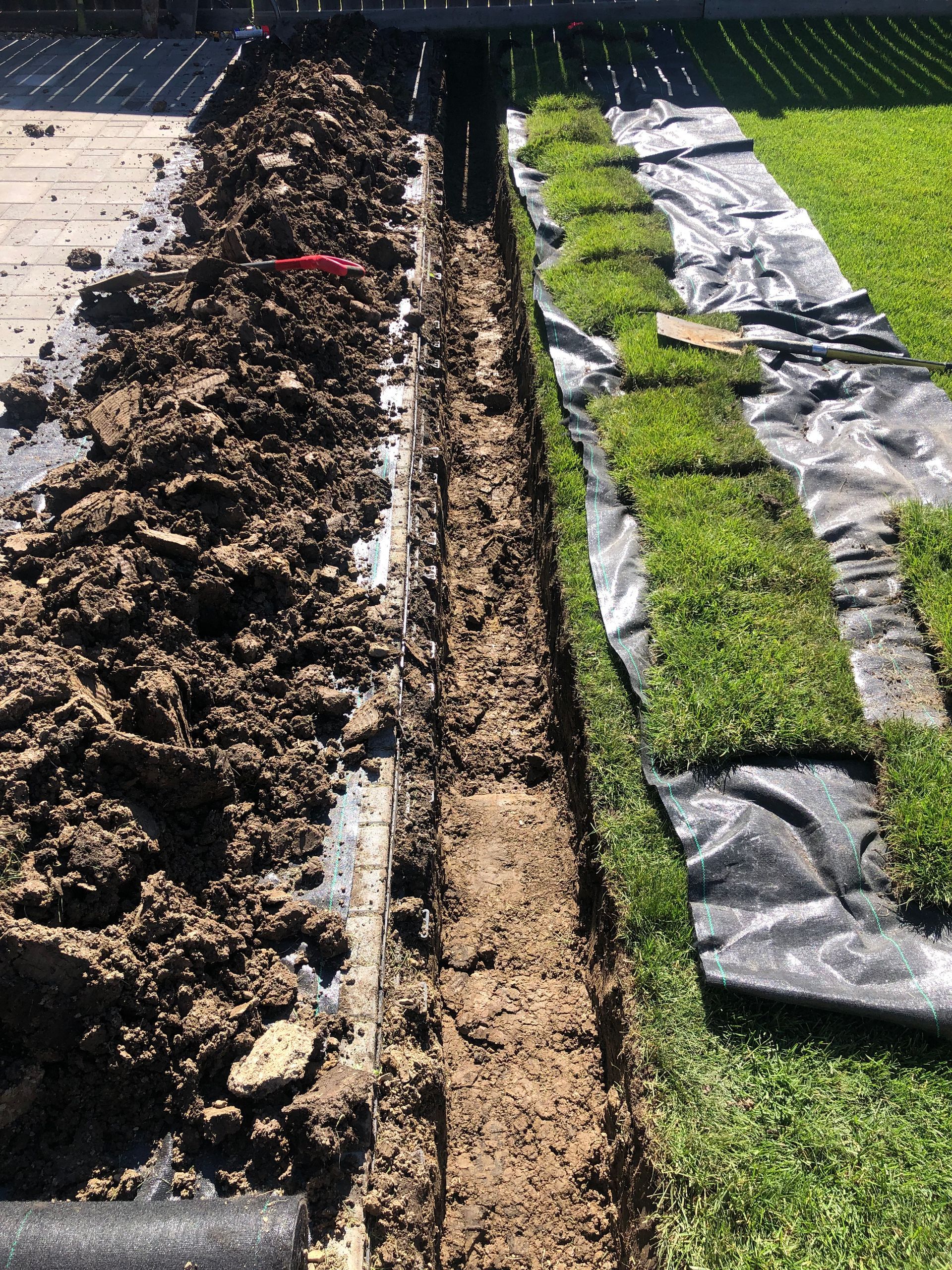 A pile of dirt is next to a row of grass.