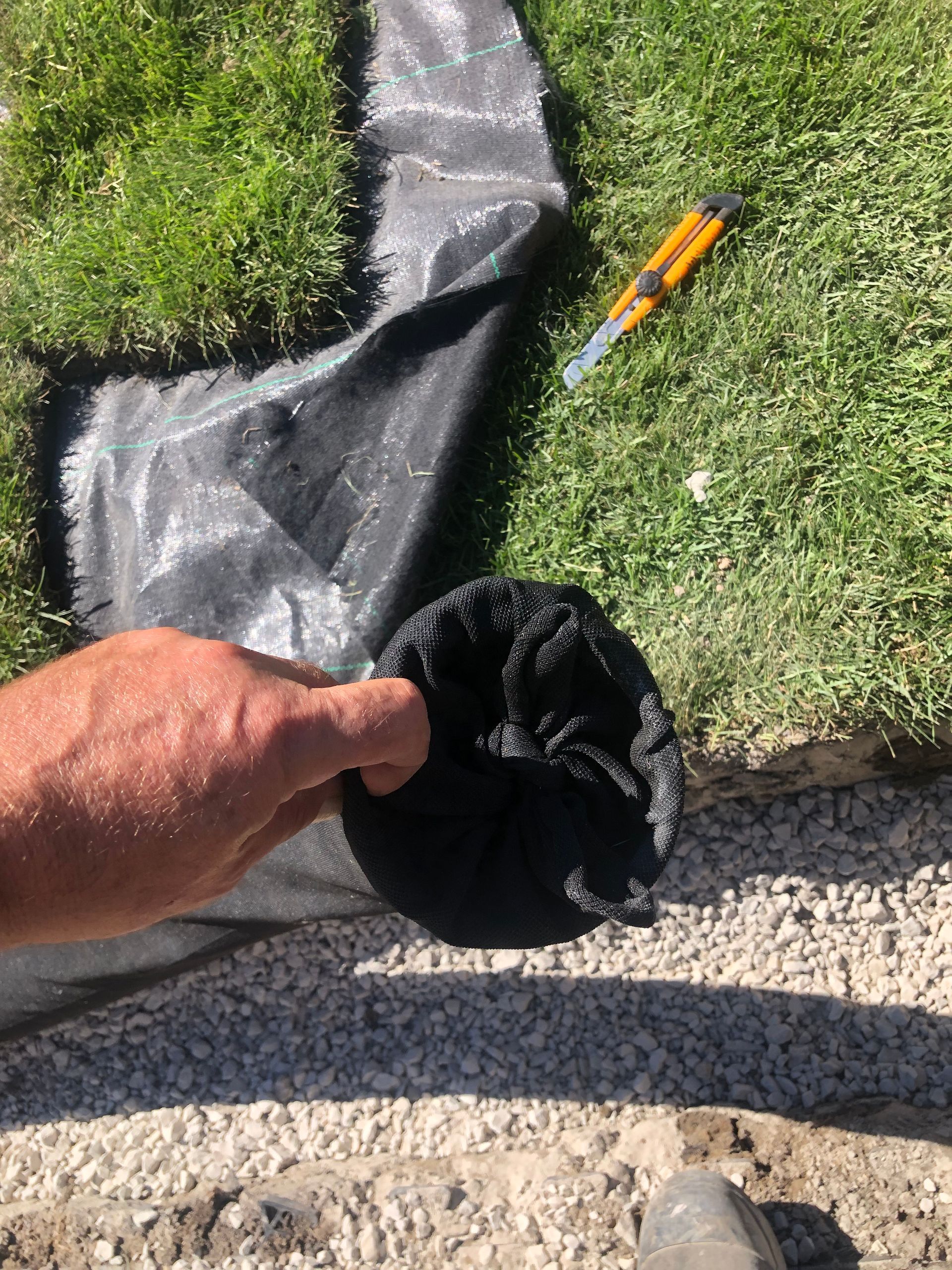 A person is holding a piece of black fabric in their hand.