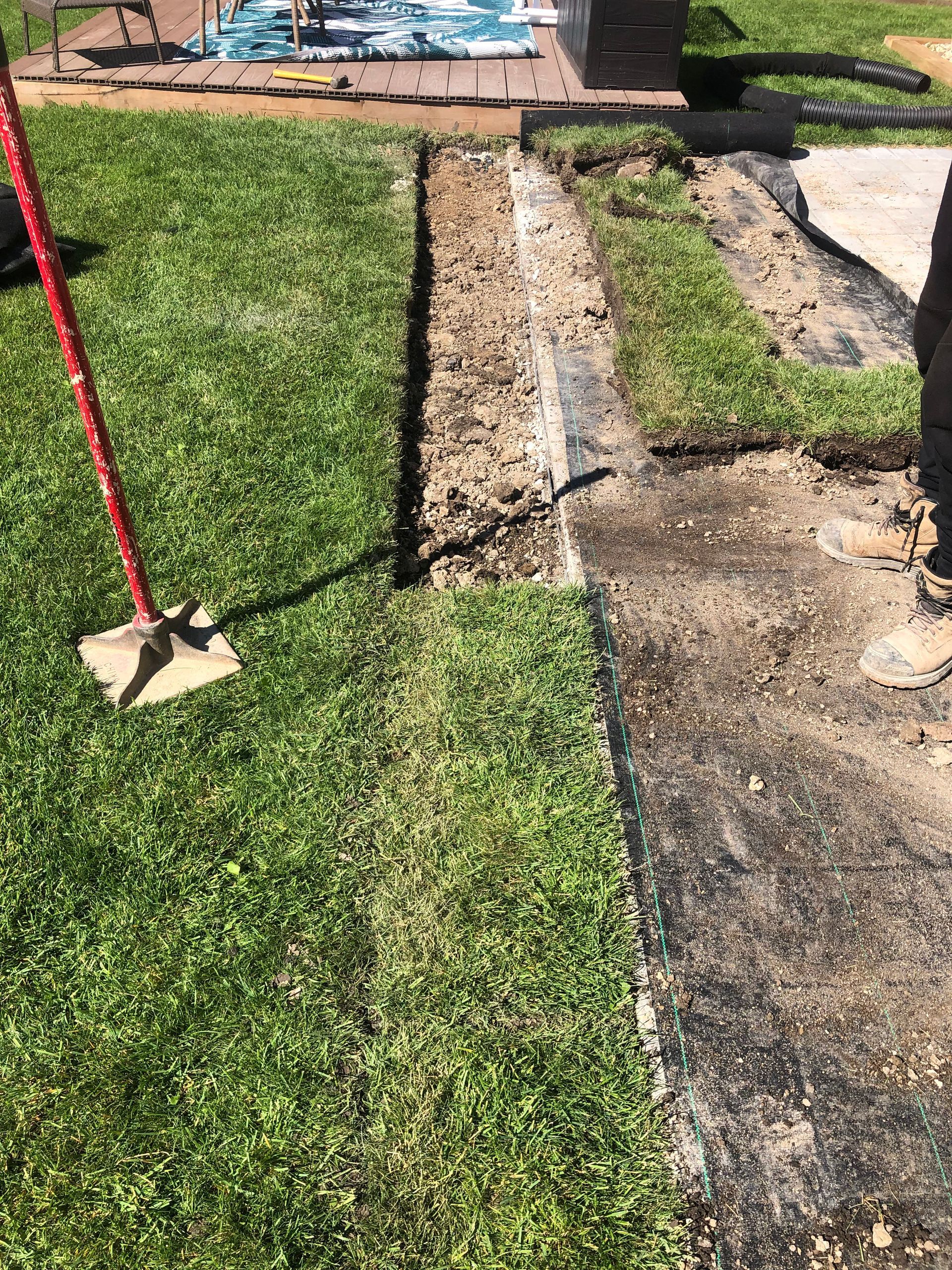 A person is standing next to a mop in a yard.