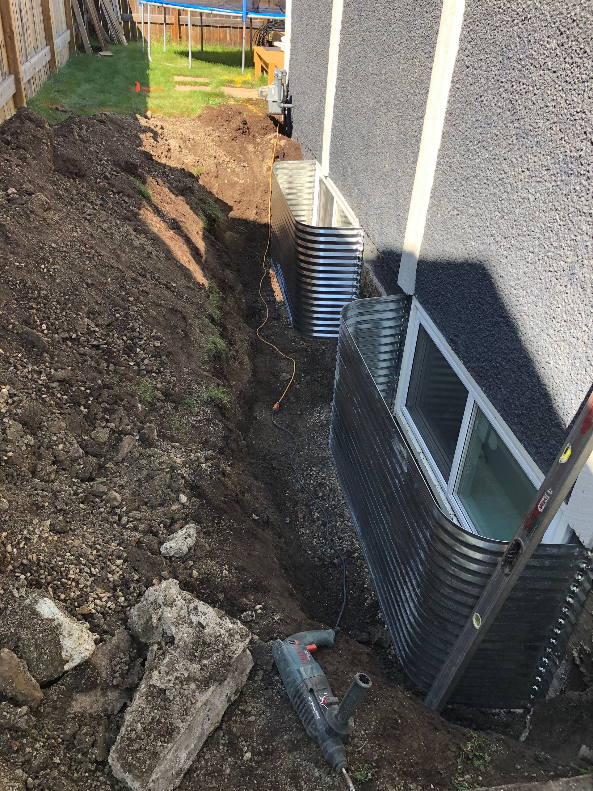 A drainage system is being installed on the side of a house.