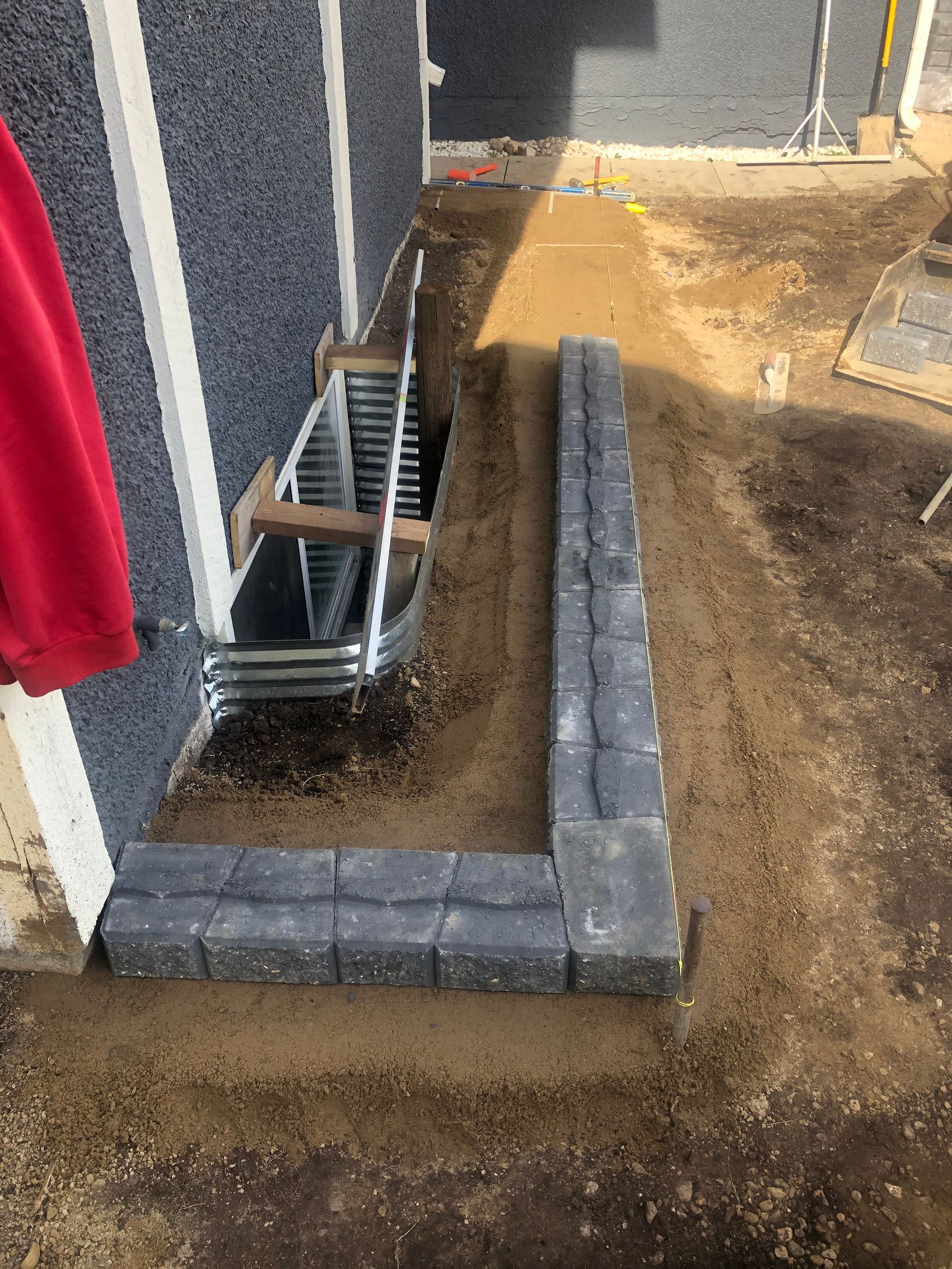 A ladder is sitting on top of a pile of dirt next to a building.