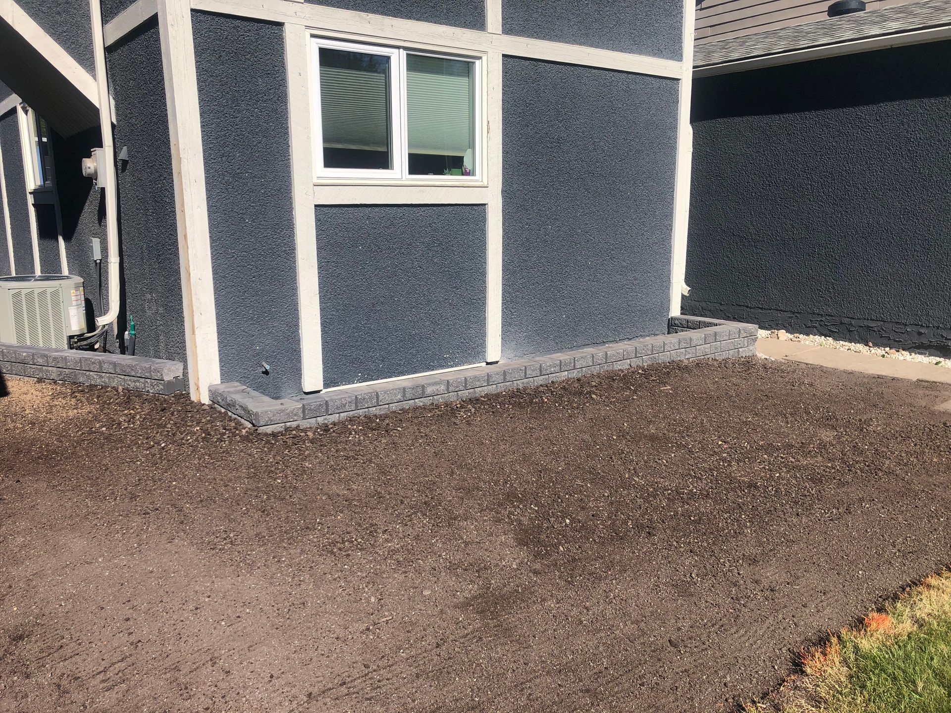 A house with a window and a lot of dirt in front of it.