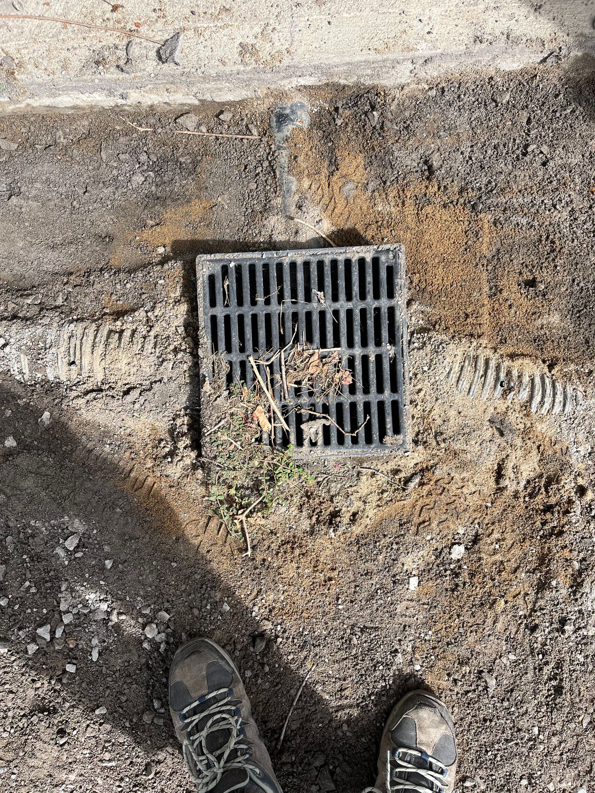 A person is standing next to a drain cover on the ground.