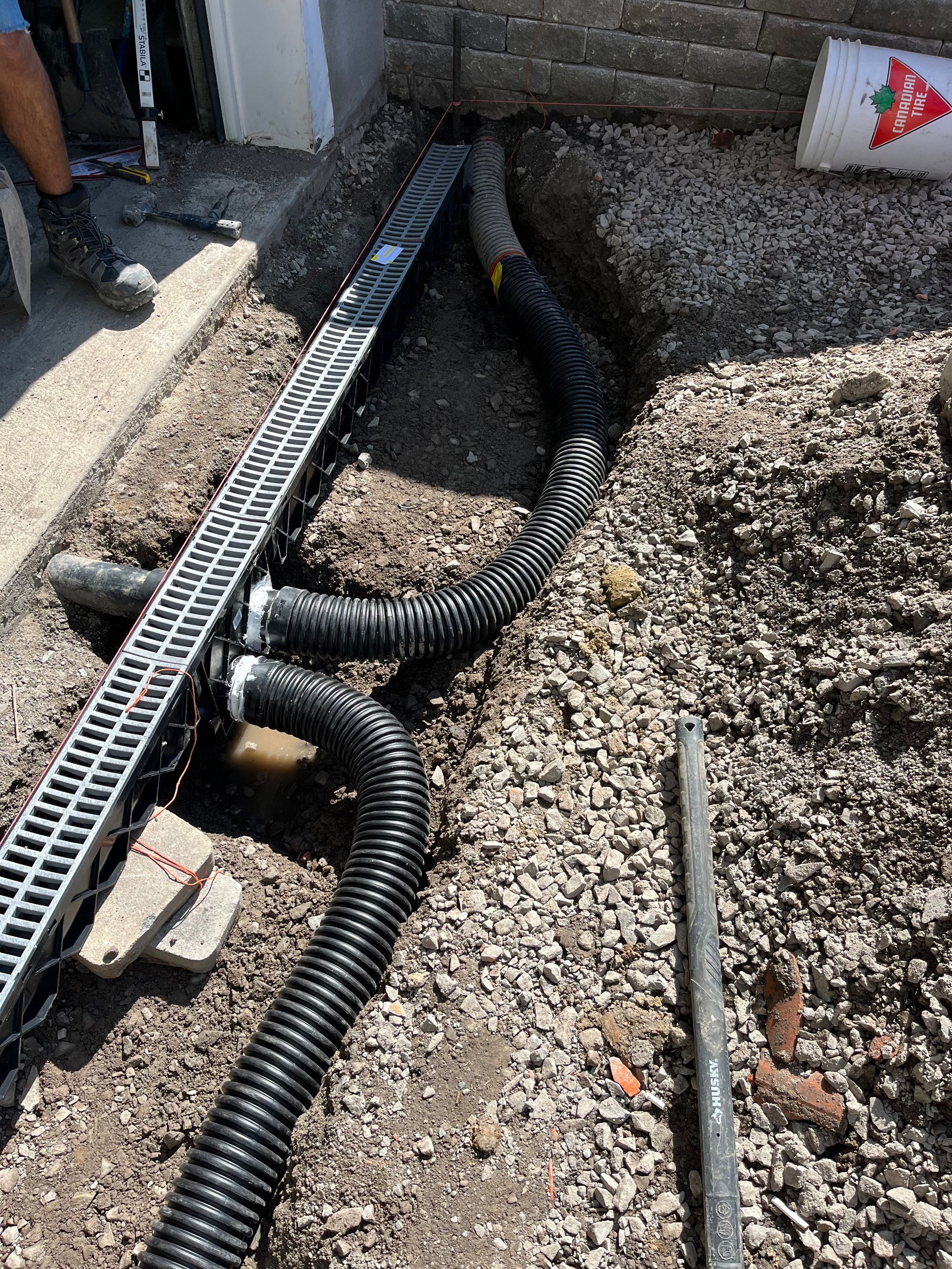 A man is digging a hole in the ground to install a drain.