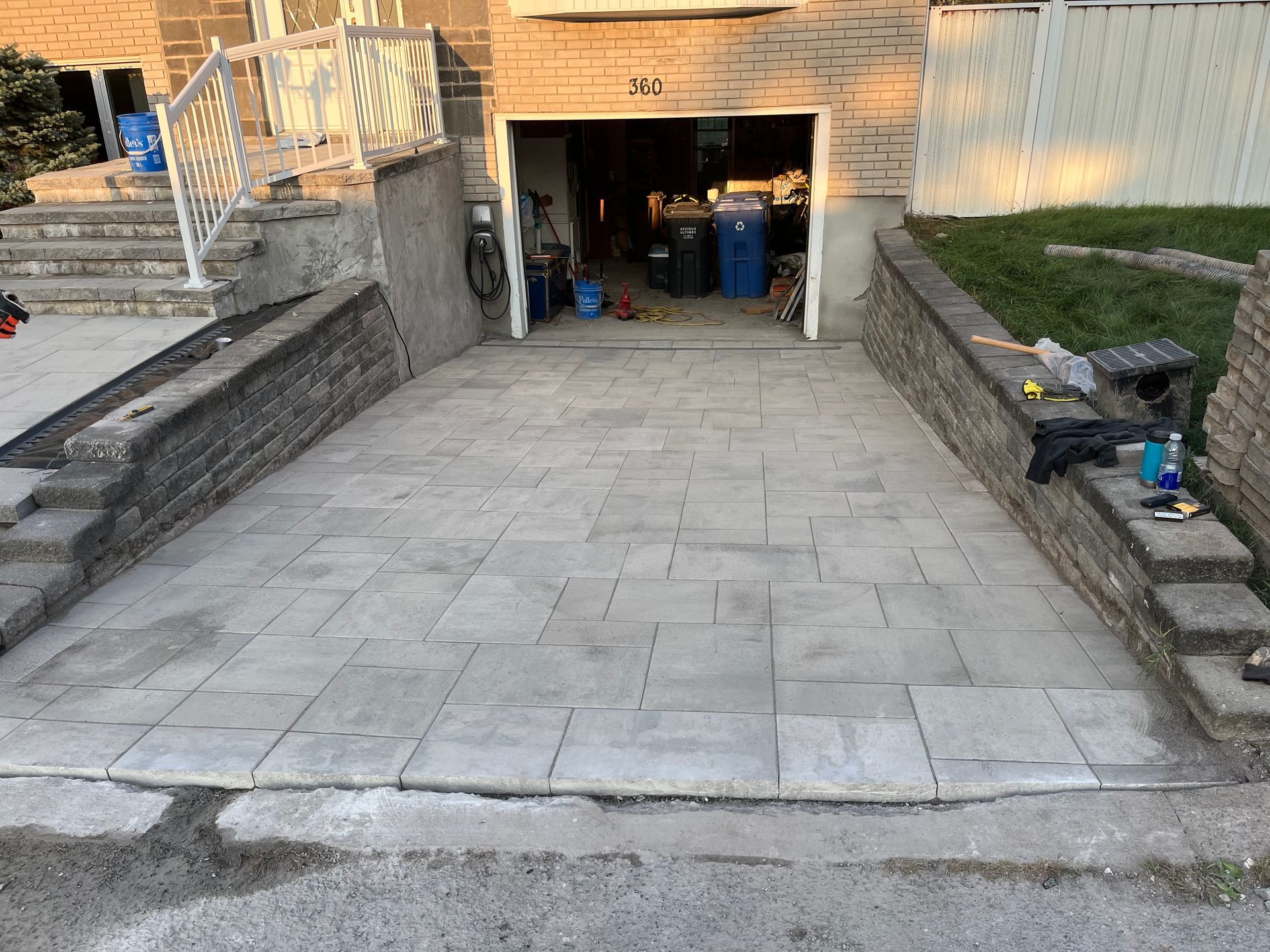 A driveway leading to a garage with a brick wall and stairs.